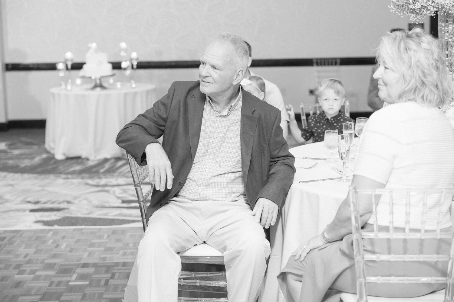 A casual moment captured during a wedding reception with guests seated at tables.