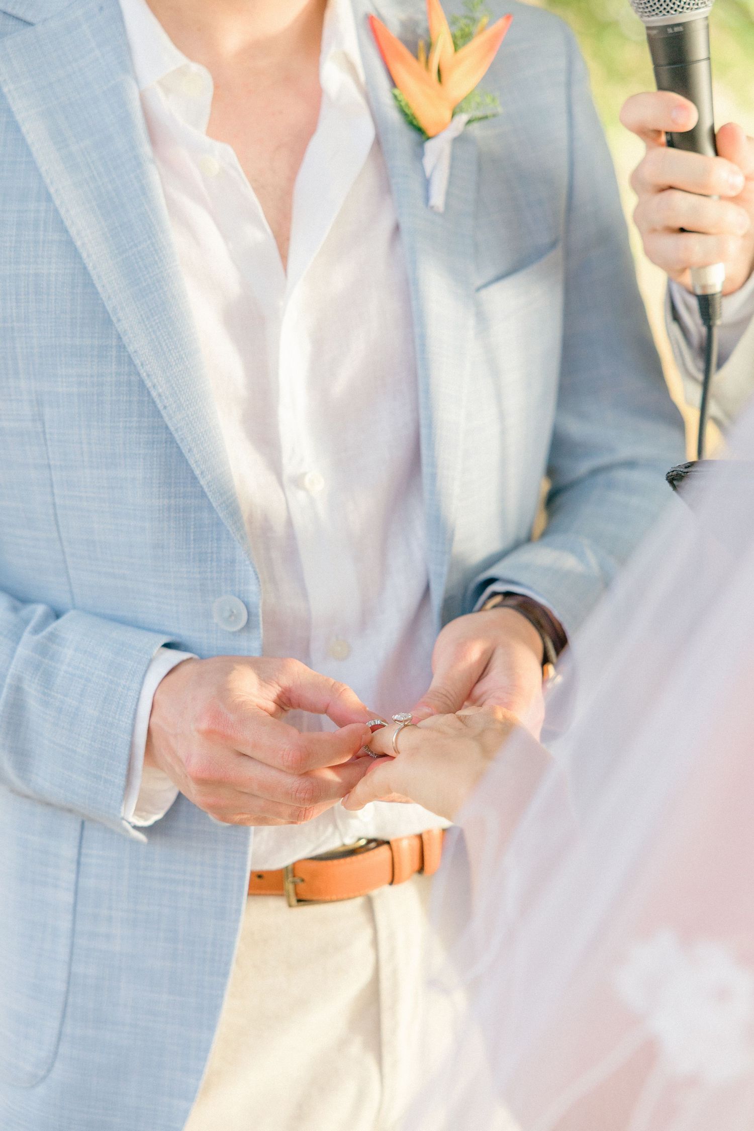 Close-up details of light blue suit jacket and white shirt with floral boutonniere.
