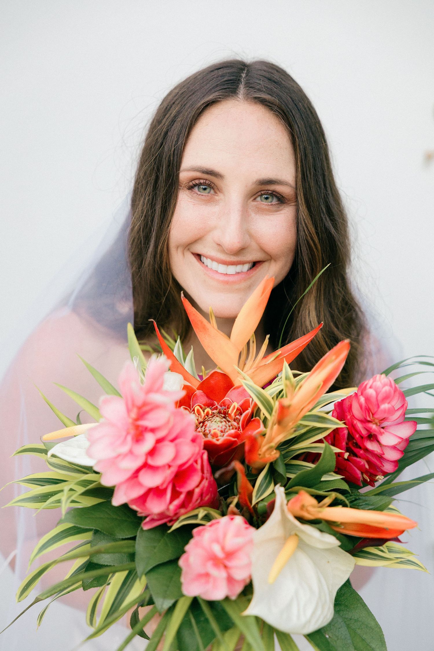 A vibrant tropical bouquet with birds of paradise and pink flowers against a white background.
