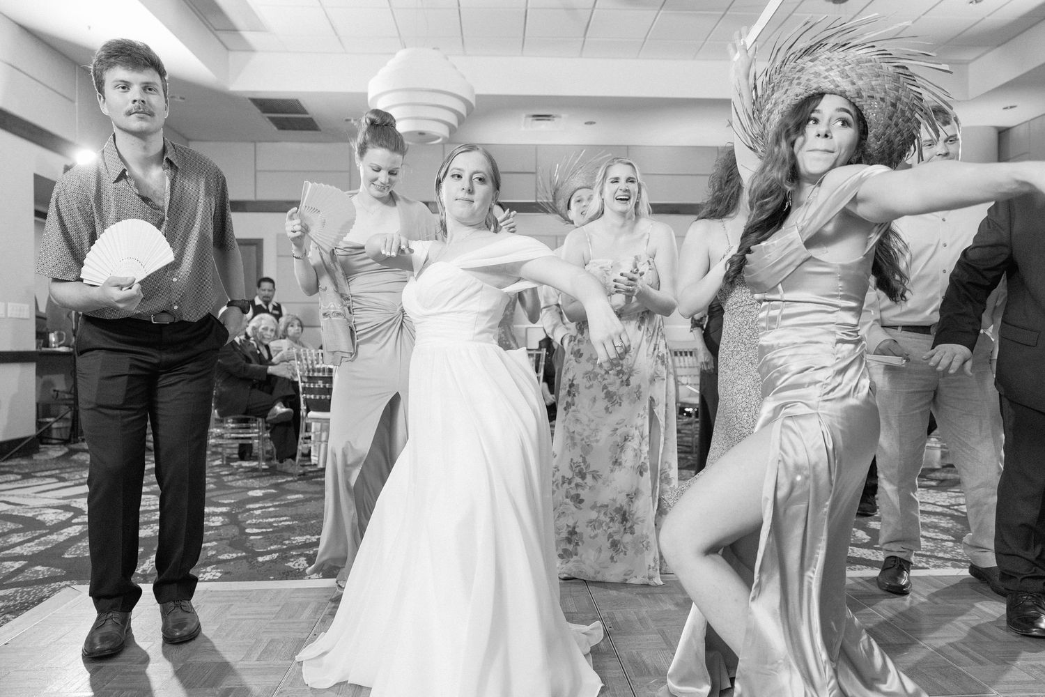 Black and white photo of wedding guests dancing and celebrating at a reception.