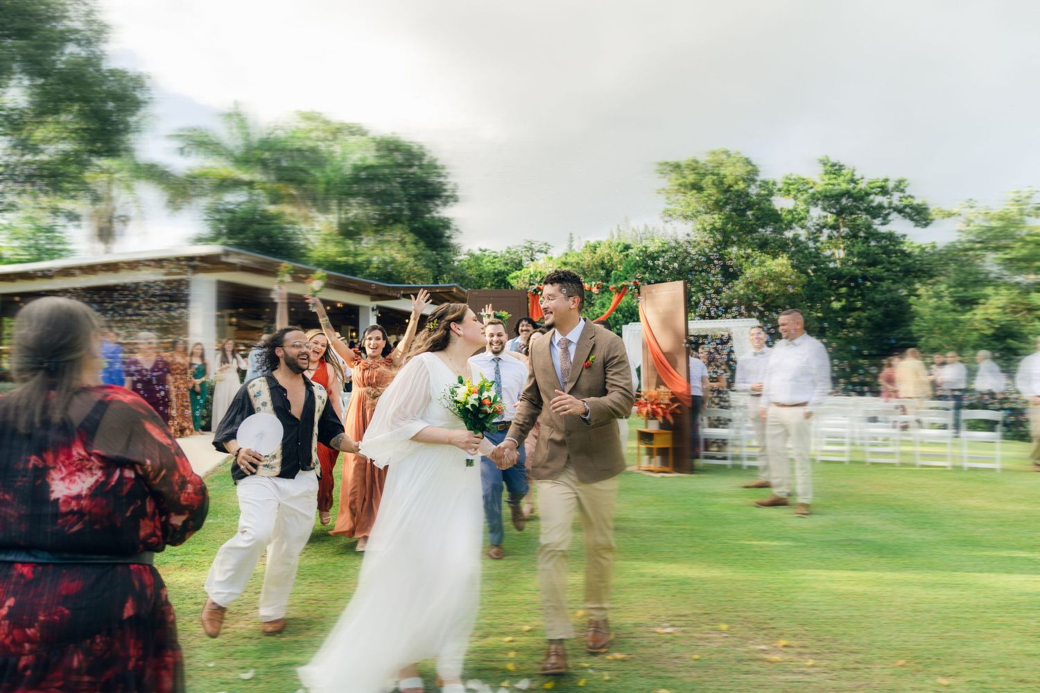 Wedding celebration with guests dancing outdoors in a garden setting.