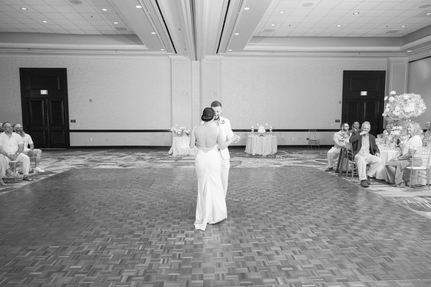 Wedding guests dance together on a patterned ballroom floor during an elegant reception celebration.