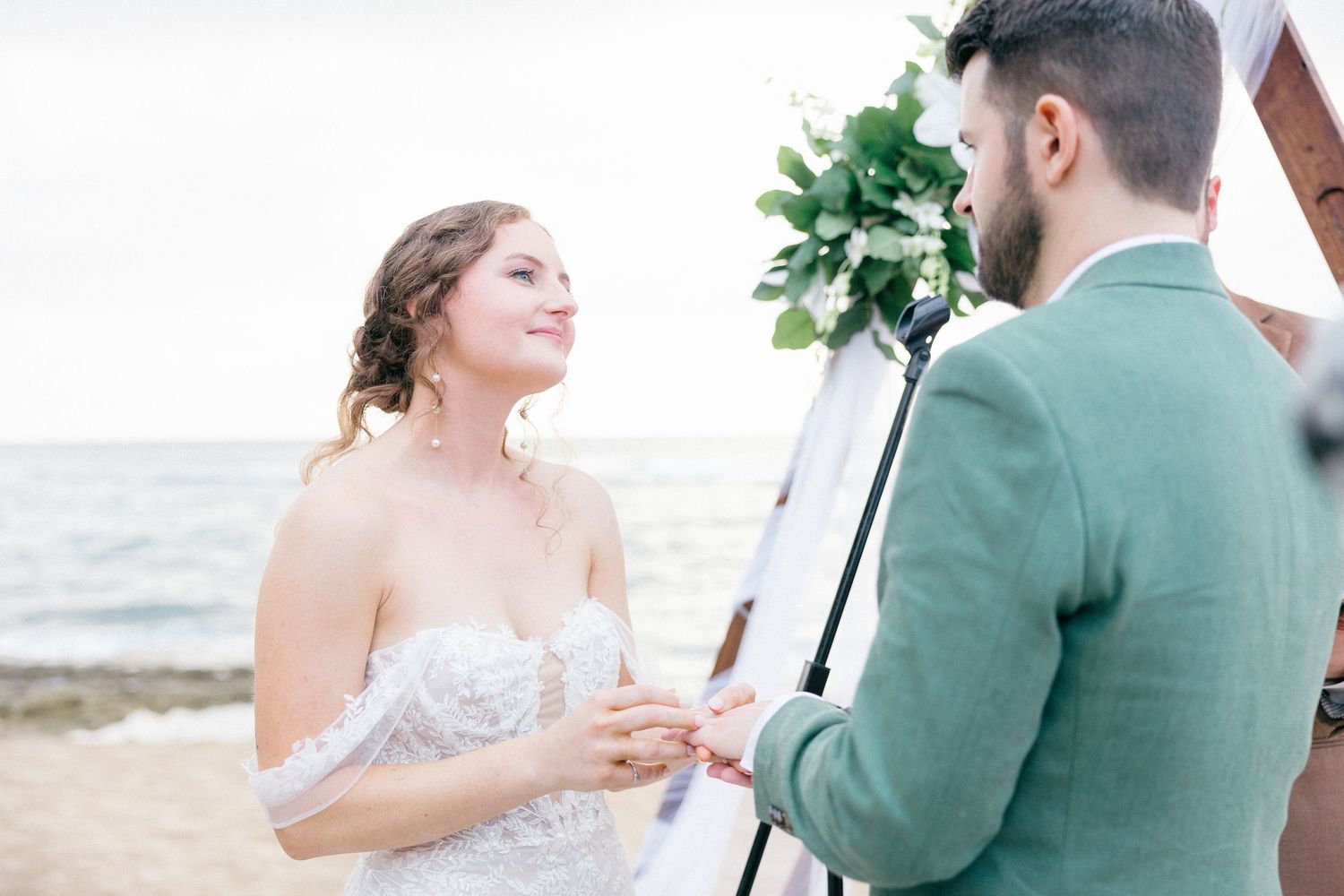 Couple exchanging vows during seaside wedding ceremony with ocean backdrop.