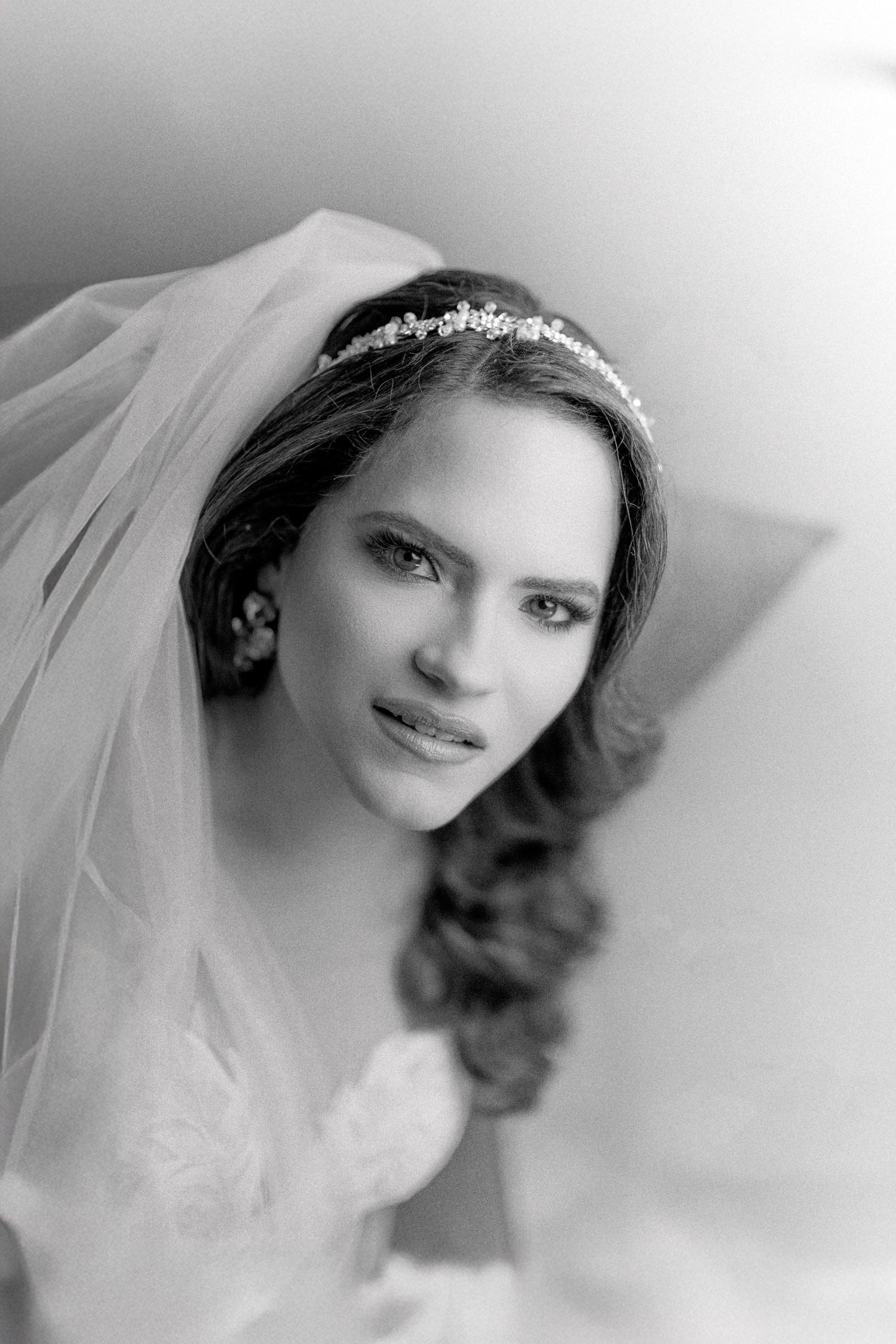 A soft black and white portrait of a bride wearing a delicate veil and classic wedding attire.