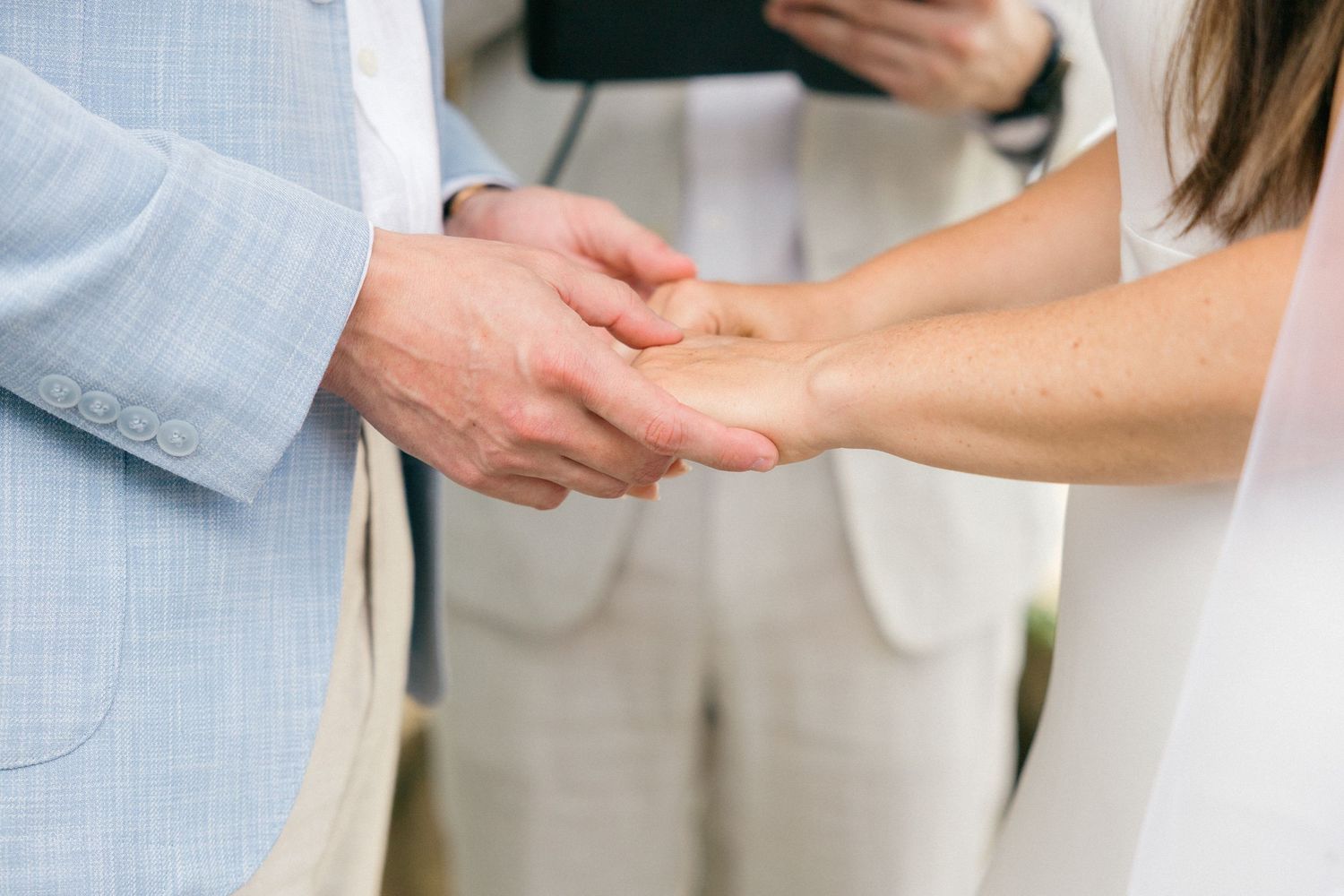 Close-up of hands during wedding ceremony exchange.