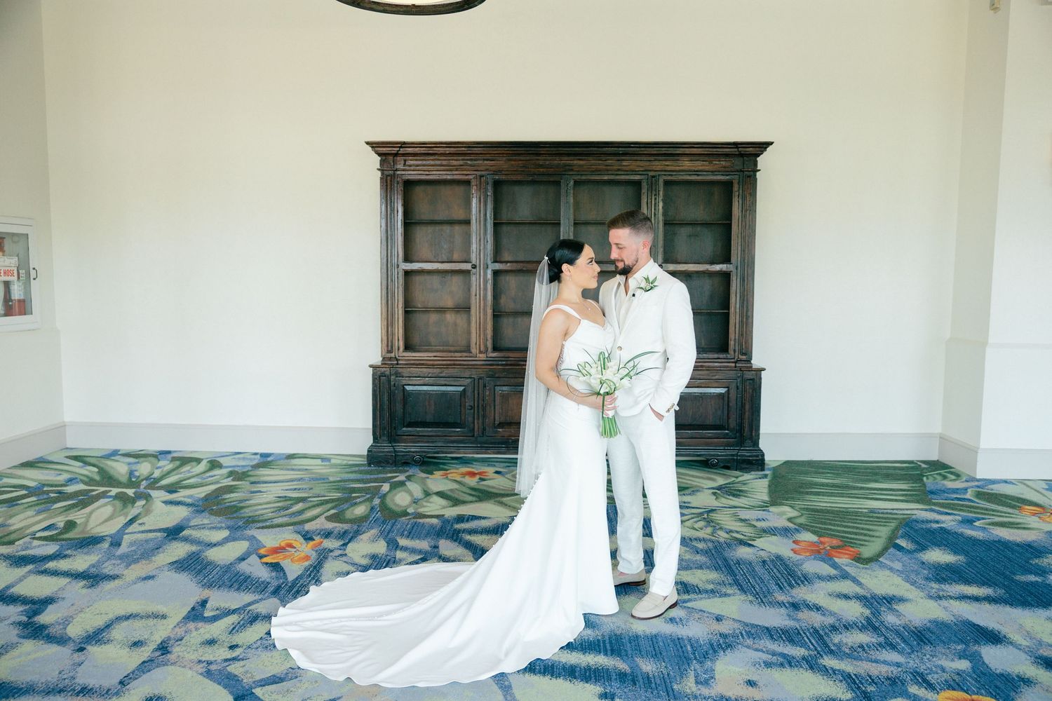 Elegant wedding photos taken in interior space with patterned carpet and dark wood panels.