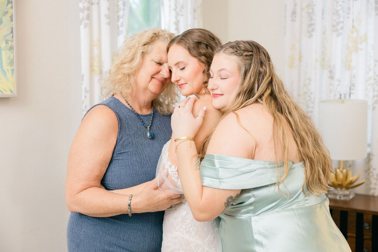 Tender moments captured between bridesmaids in blue dresses during pre-wedding preparations.