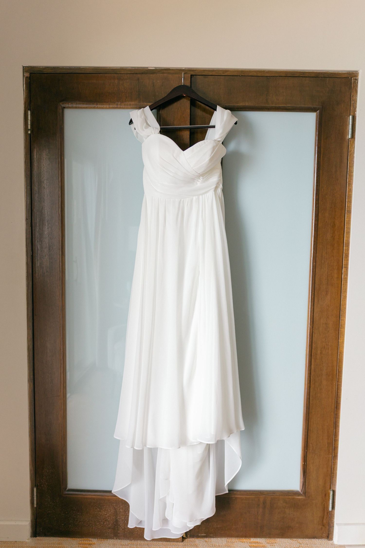 White wedding dresses hanging on wooden doors in a bridal preparation room.