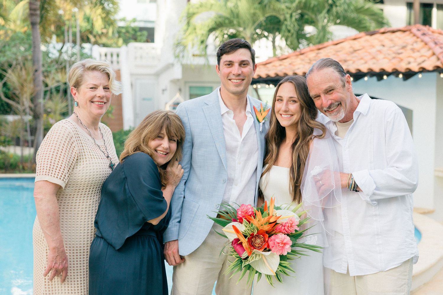 Wedding party group photo with tropical flowers and palm trees in background.