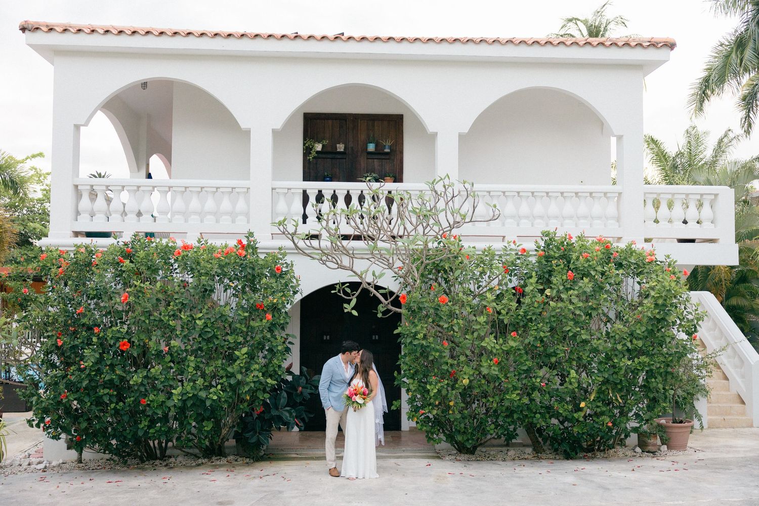 White arched walkway with tropical landscaping and flowering bushes at a luxury resort.