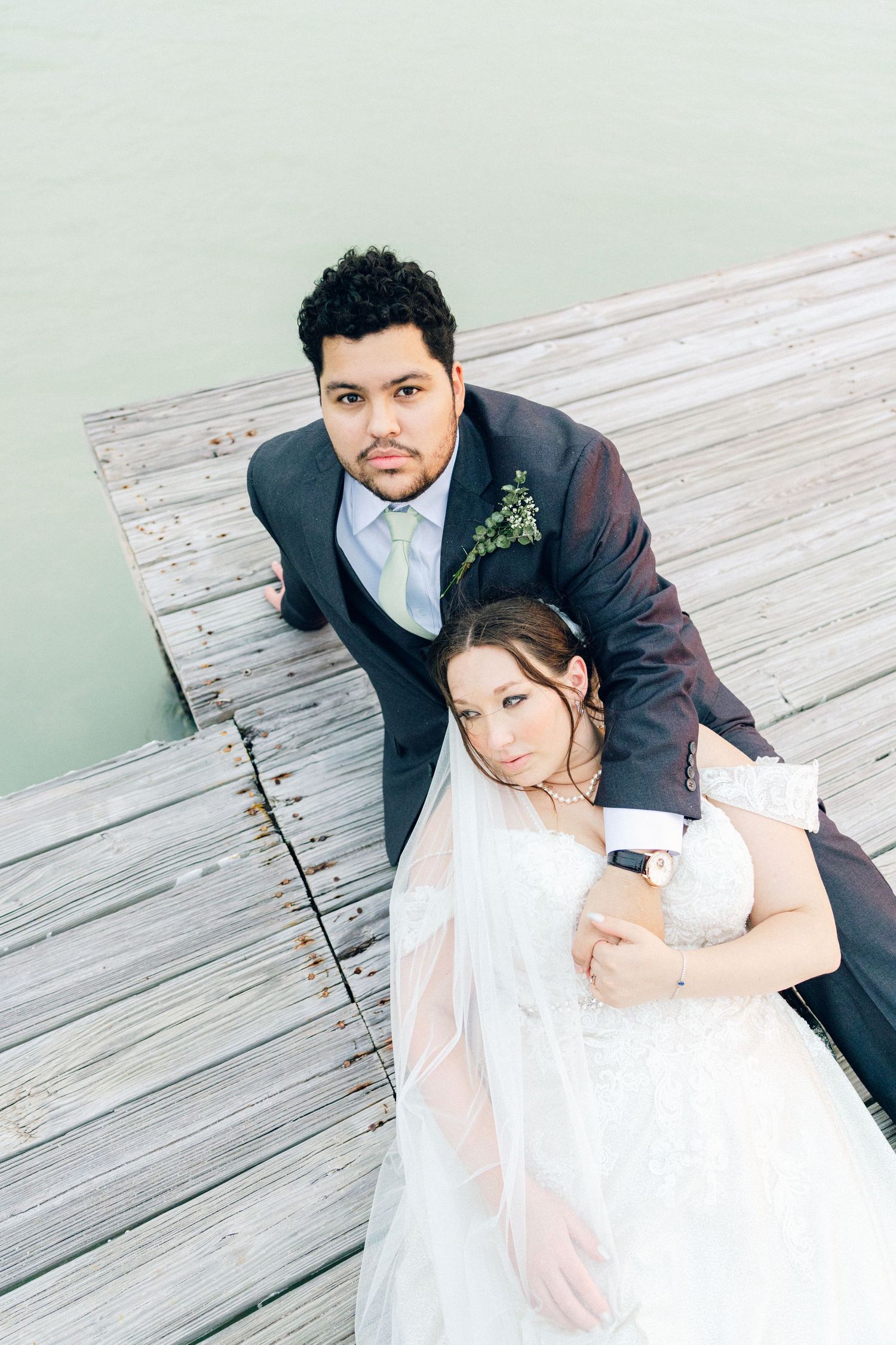Wedding couple posing intimately on a wooden deck with soft lighting.