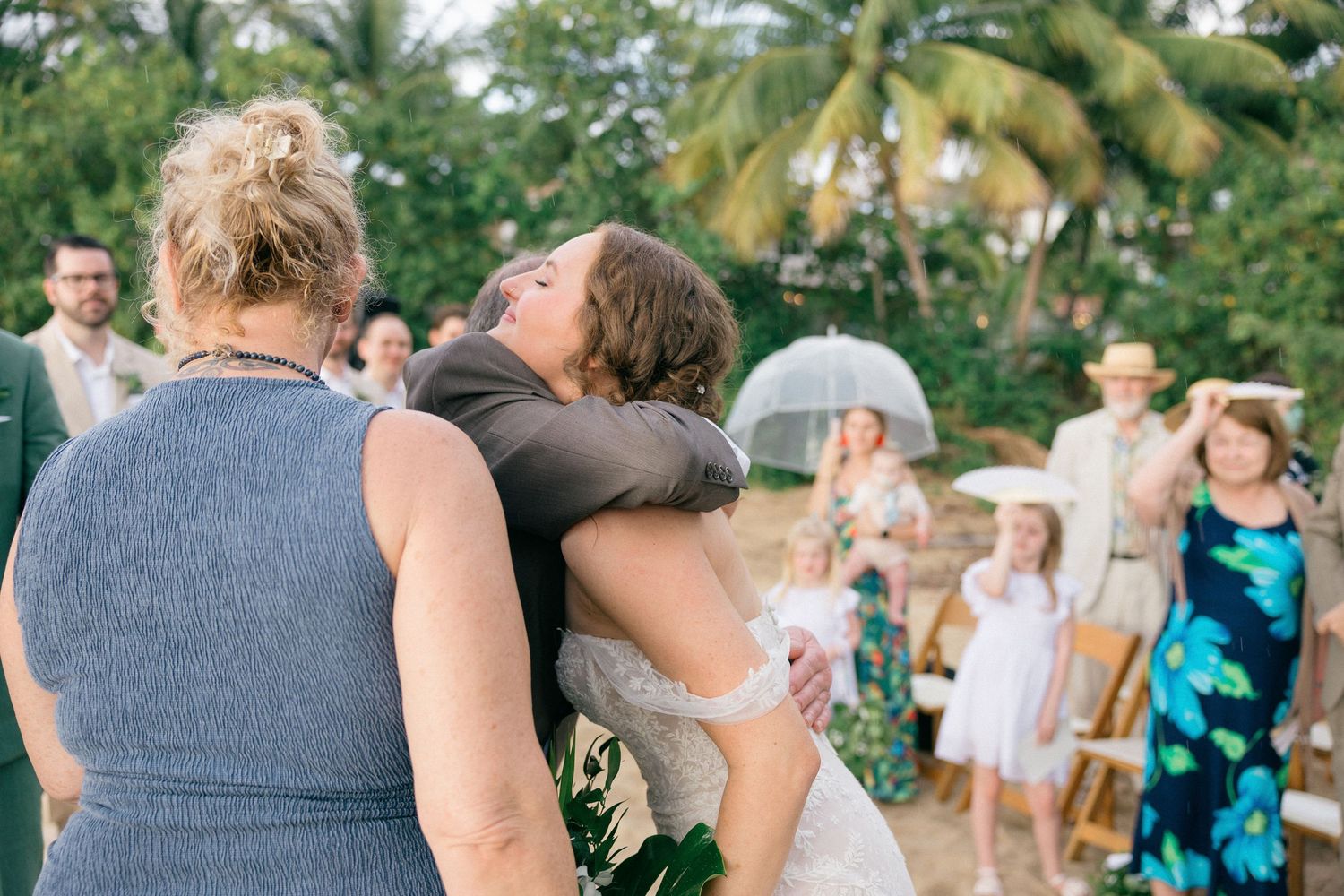Guests gather at a tropical beach wedding with palm trees in the background.