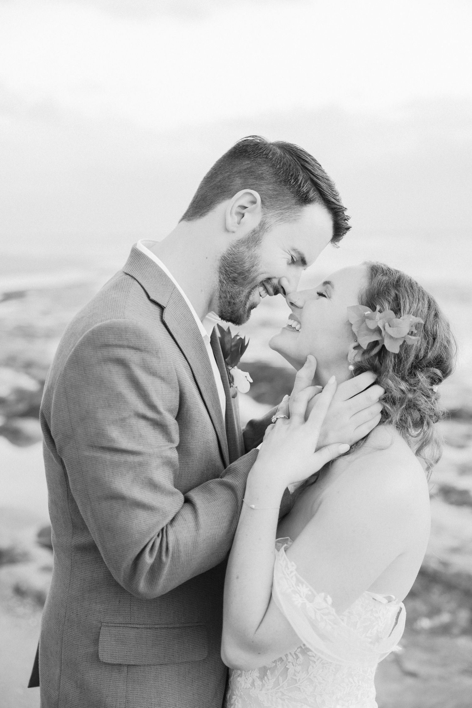 Intimate black and white portraits showing tender moments between newlyweds by the sea.