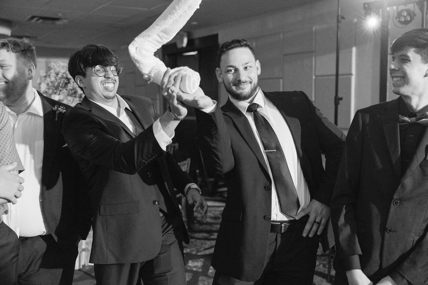 Wedding guests dance and celebrate together at a lively reception party in black and white.