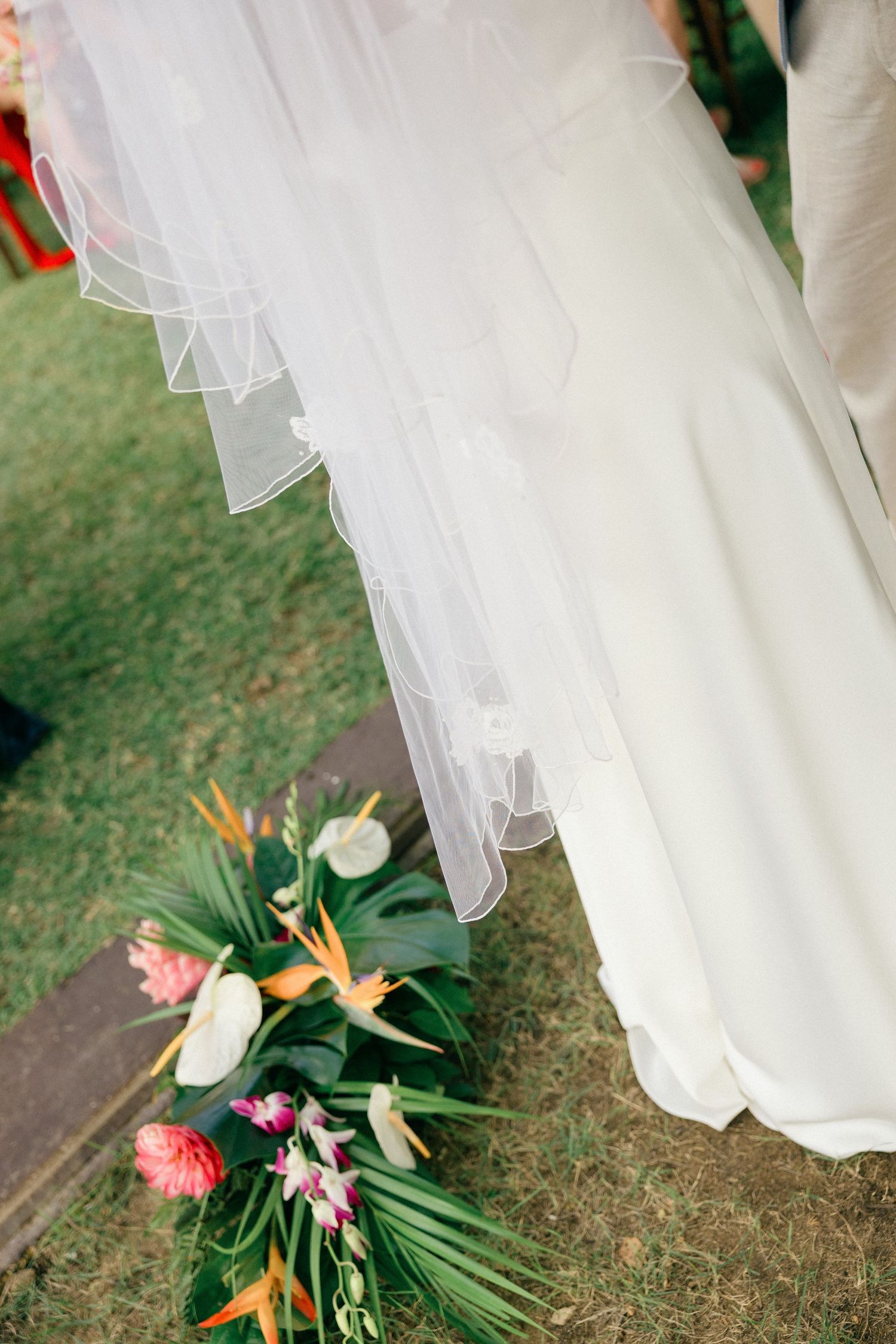 Tropical floral arrangement with birds of paradise and protea sits beneath flowing white wedding dress.