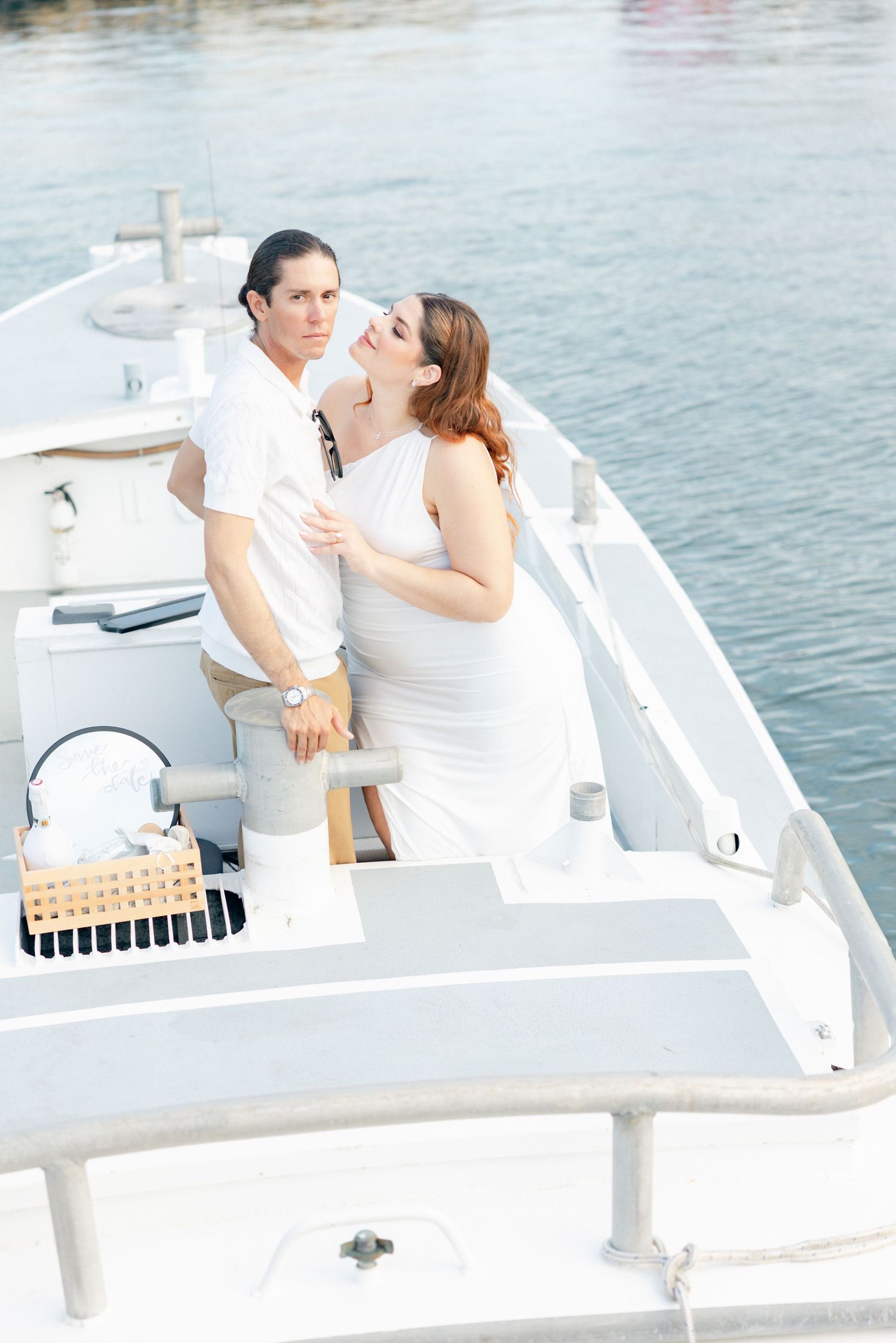 A couple shares intimate moments on a white boat deck overlooking the water.
