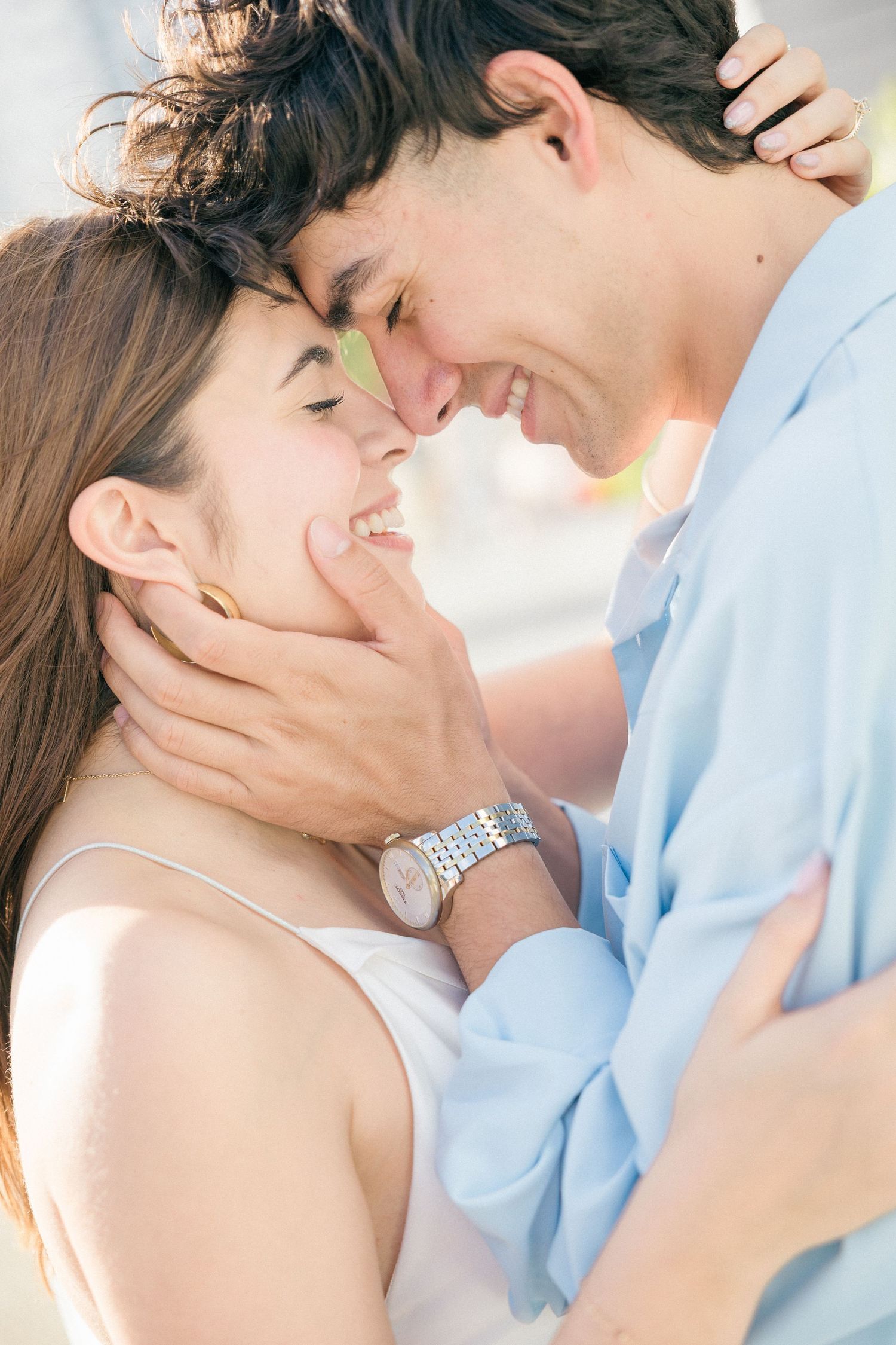 A romantic couple sharing an intimate moment with foreheads touching and gentle smiles.