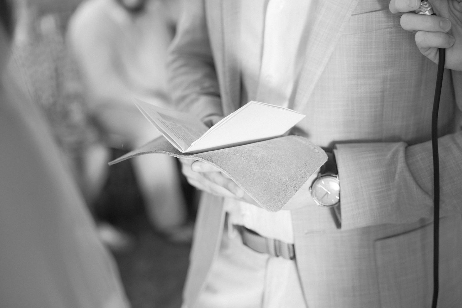Detail shots of a light gray suit jacket during a wedding ceremony.