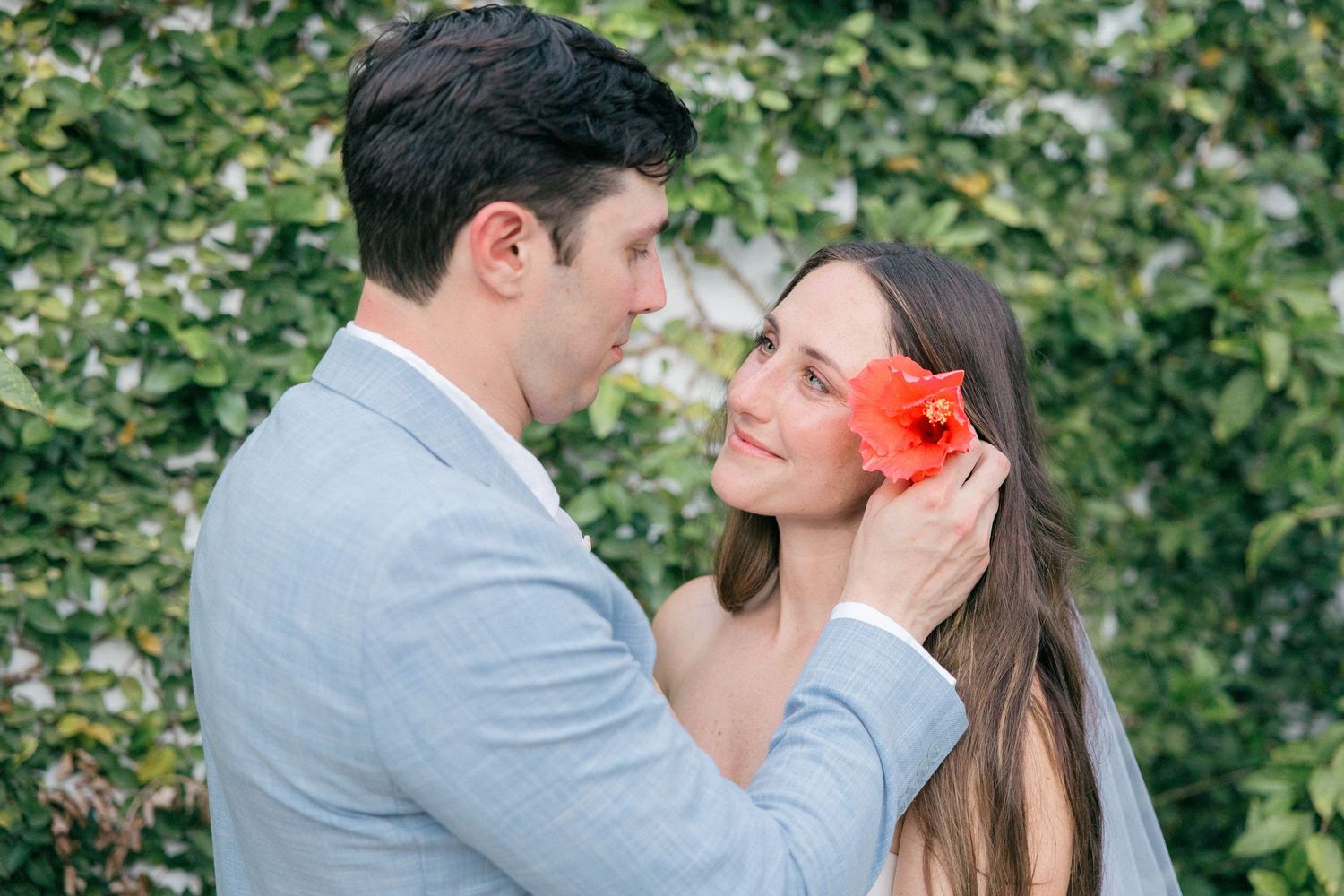 A romantic moment captured against lush green foliage in an outdoor garden setting.