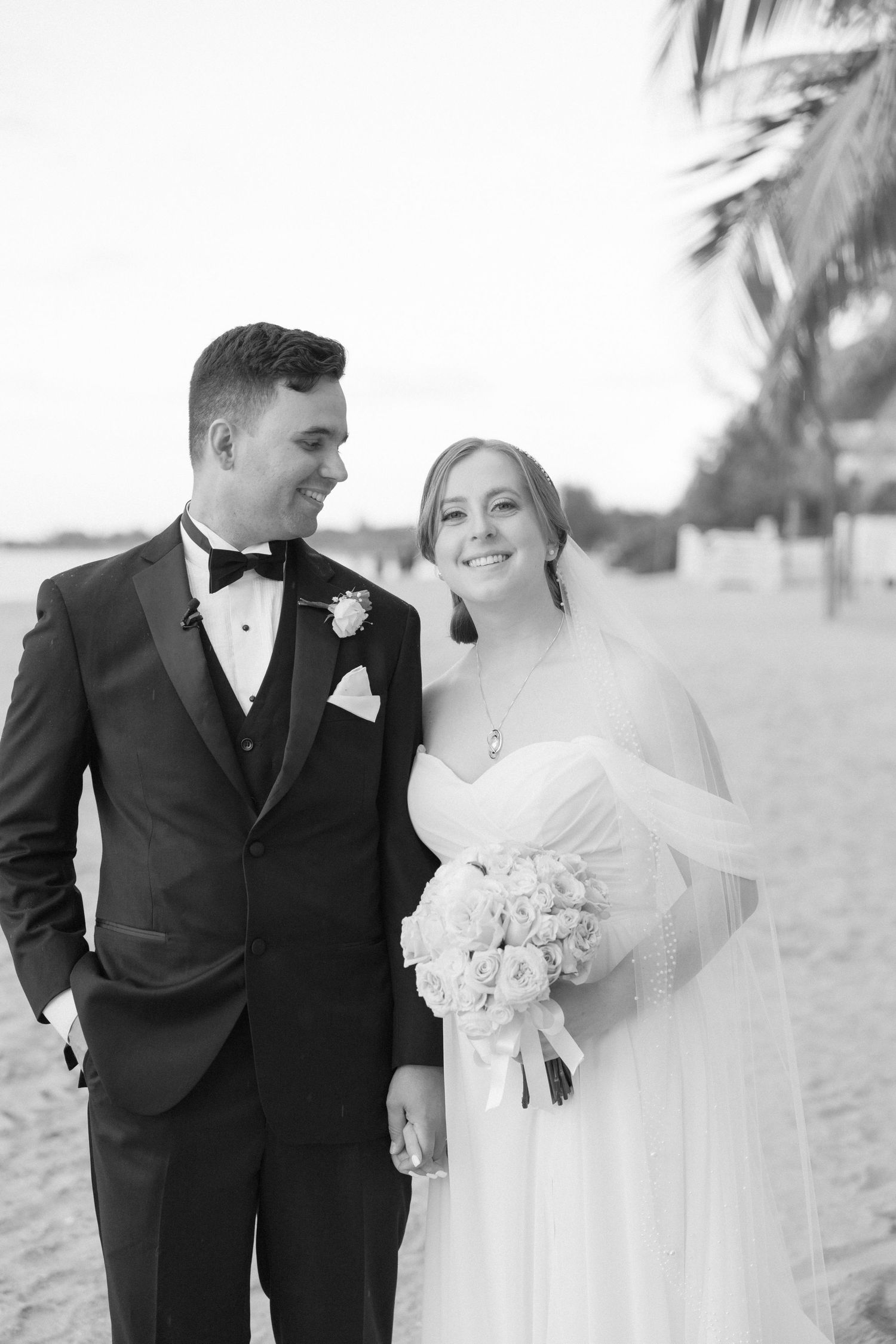 Black and white wedding photos showing tender moments between newlyweds on a beach.