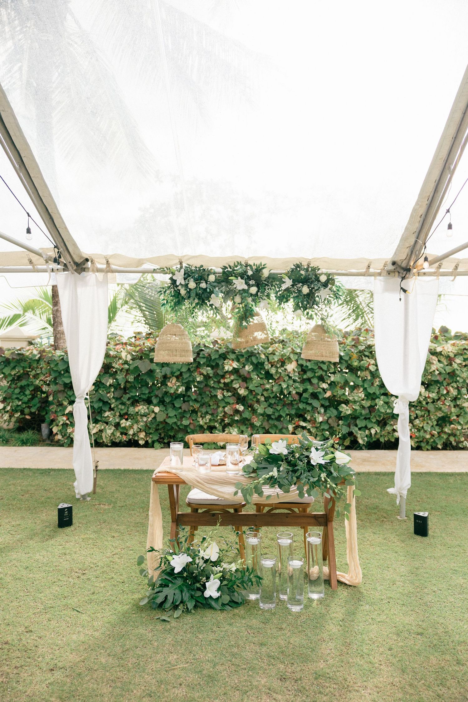 Elegant outdoor tent reception setup with white draping and greenery garlands.