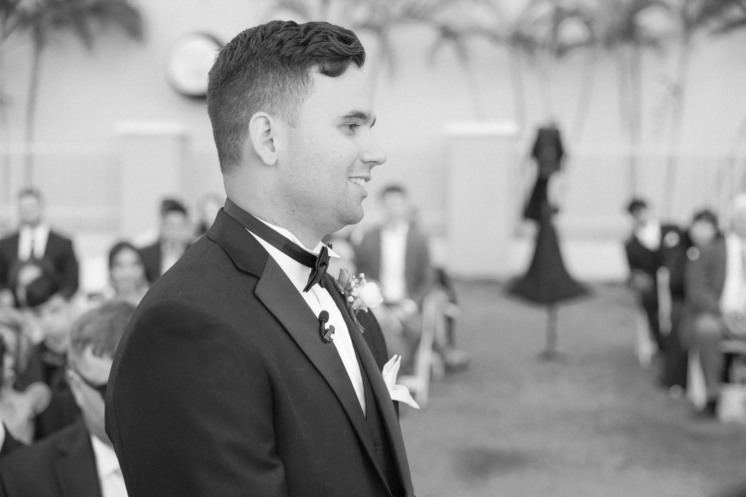 Black and white photo of wedding guests during an outdoor ceremony.