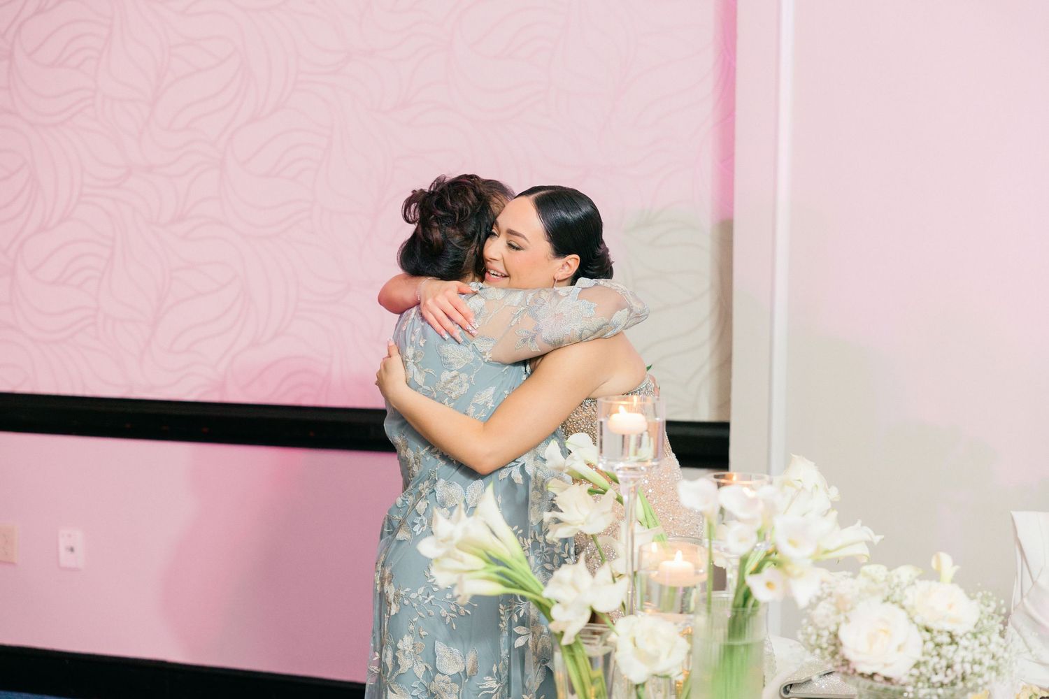 Guests hugging and celebrating during an emotional wedding reception moment.