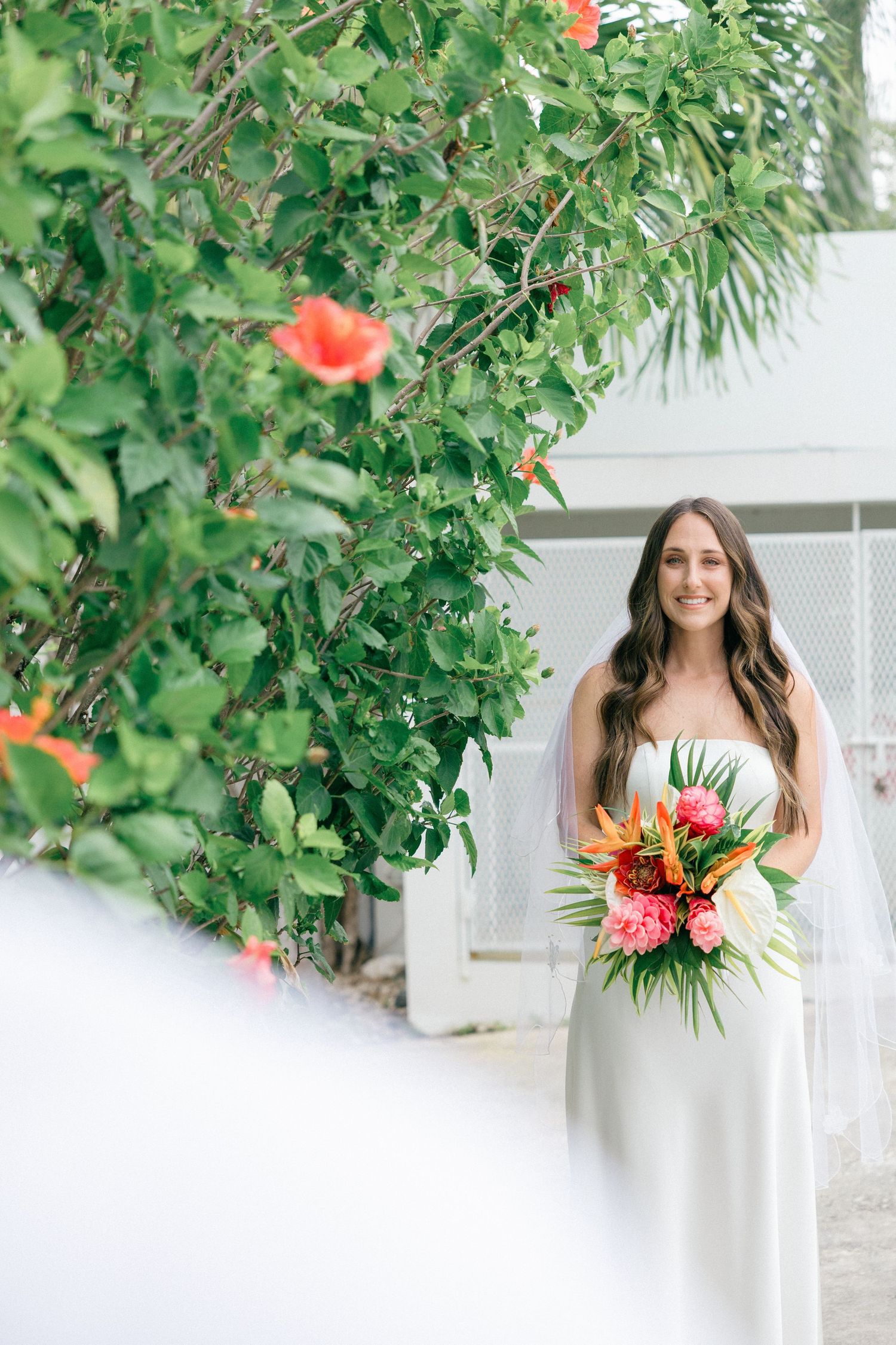 Tropical wedding photos with vibrant coral and green floral arrangements.