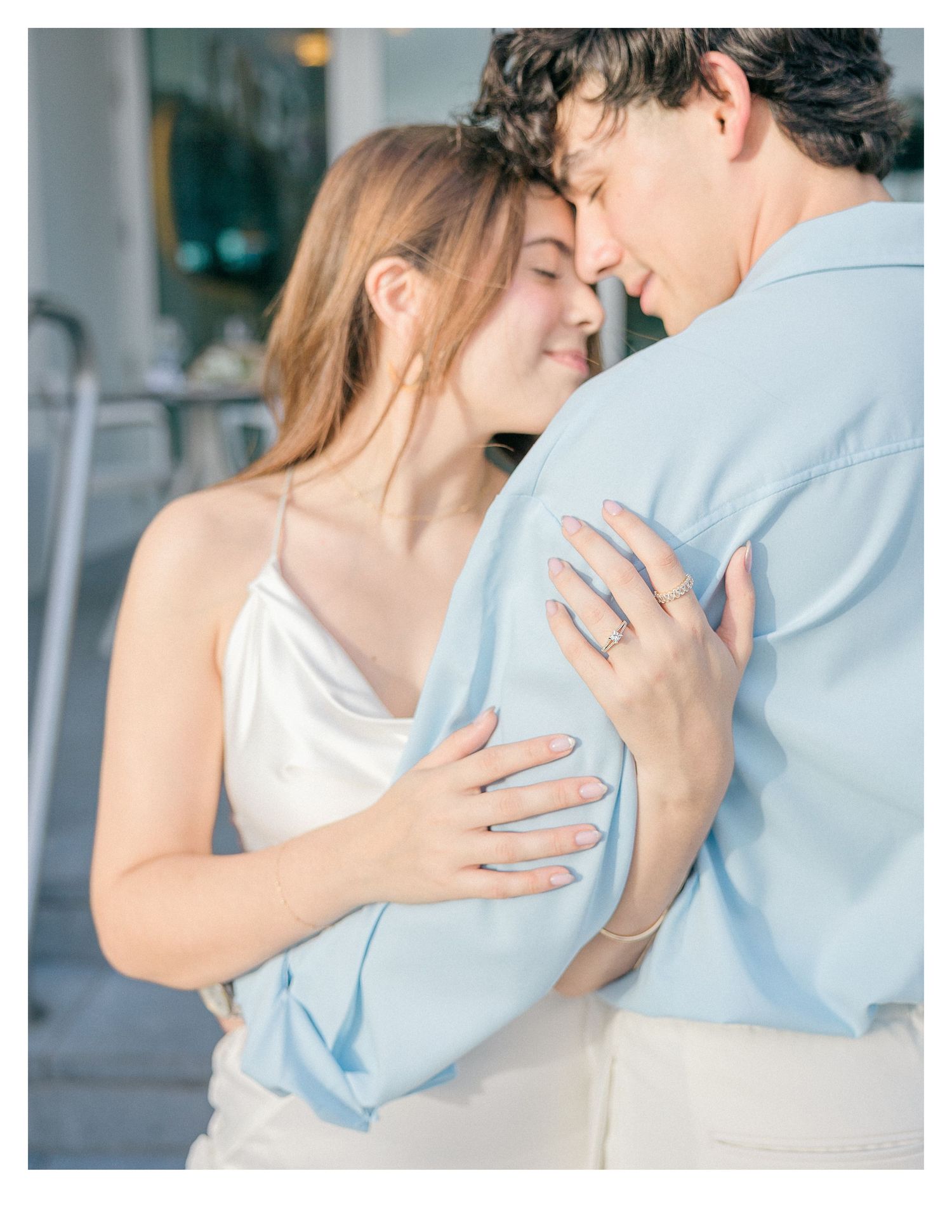 Intimate moment captured between couple with one wearing light blue and the other in white.