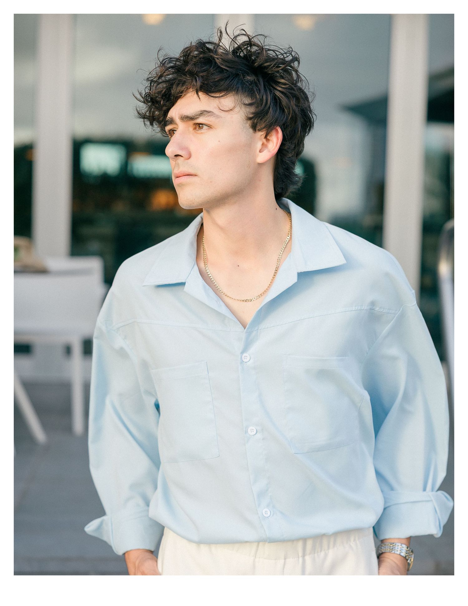 Person wearing a light blue button-down shirt in an outdoor setting.