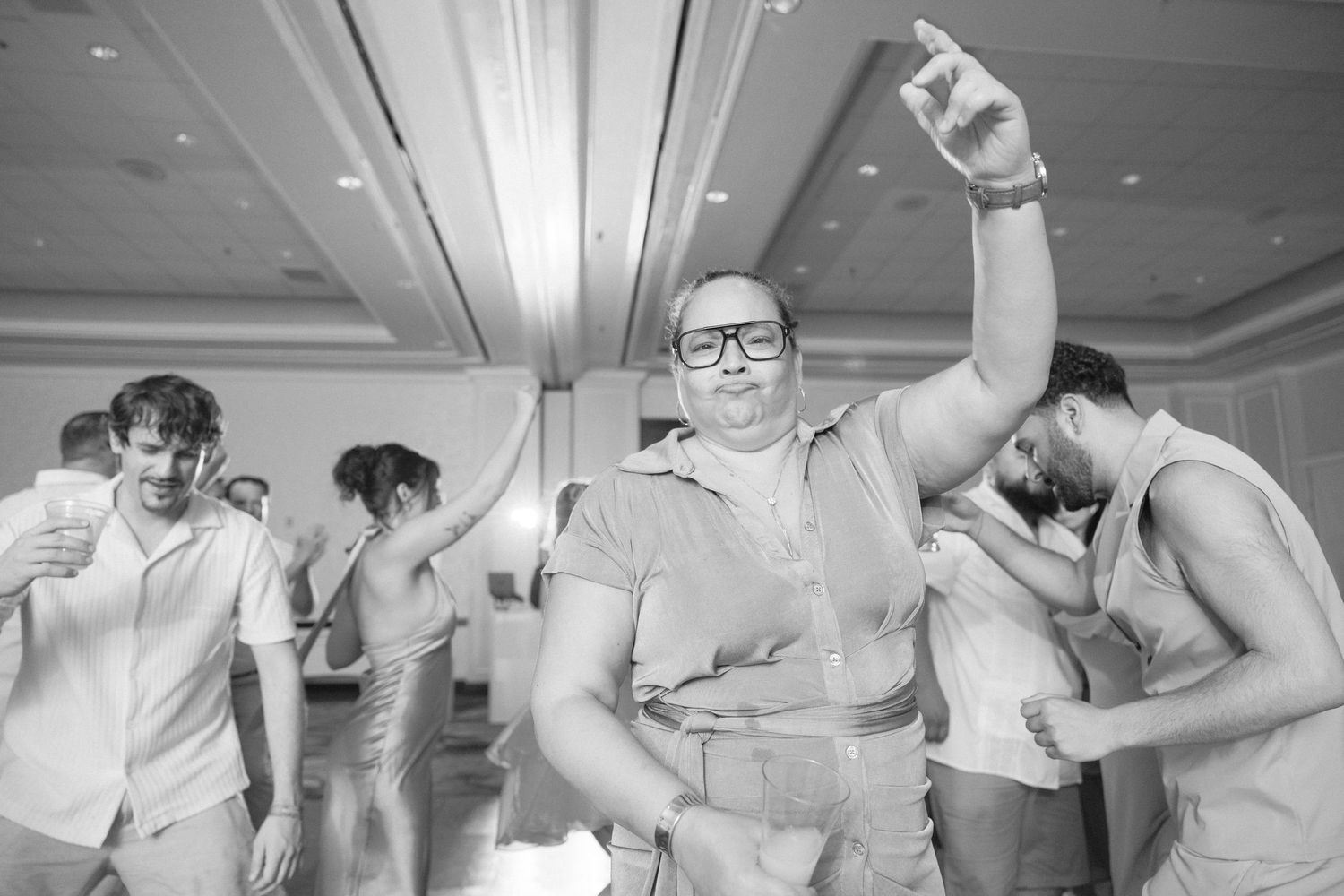 Wedding guests dancing and celebrating on a large indoor dance floor.