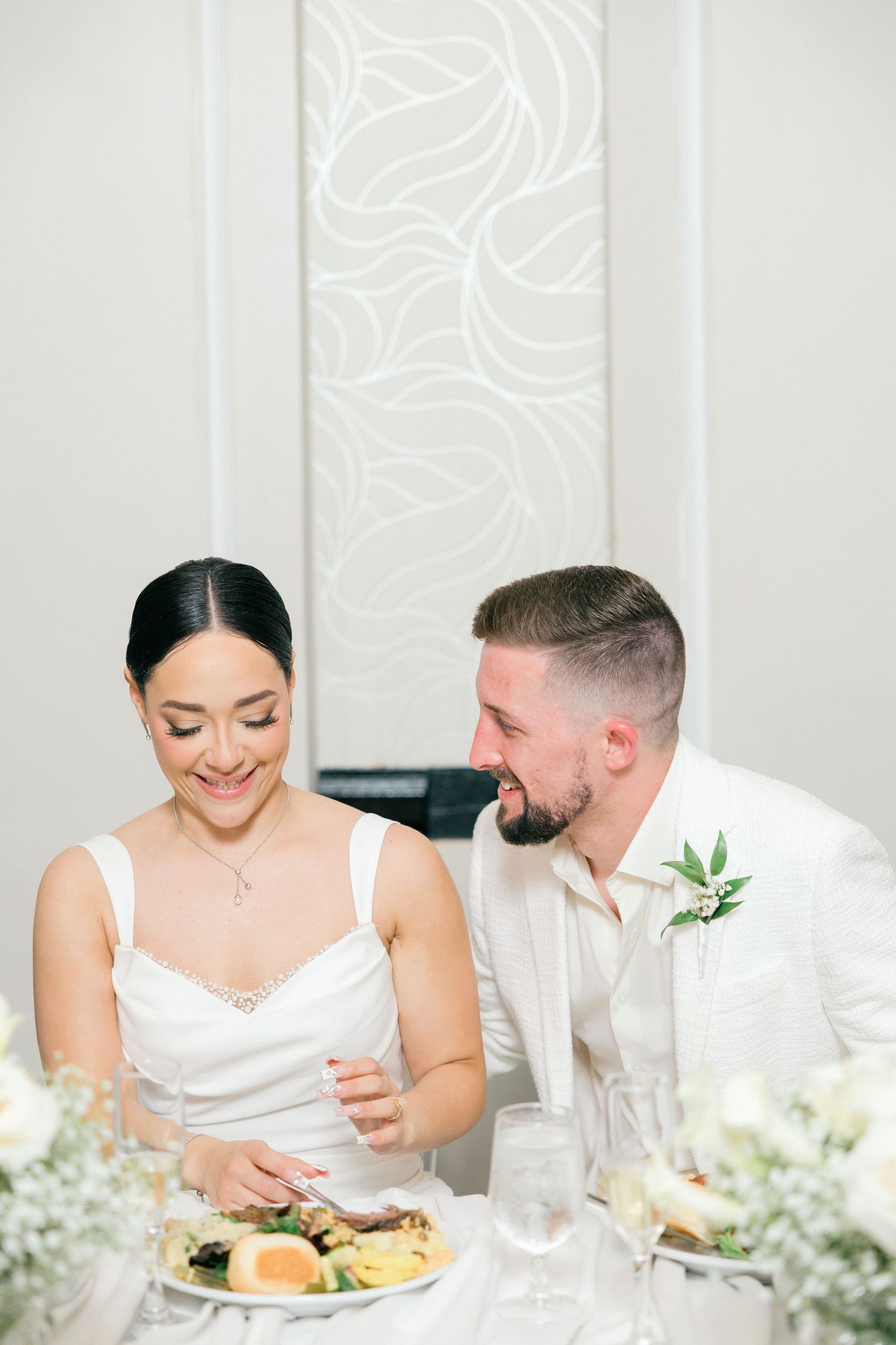 Intimate moment shared between couple at elegant white wedding reception table.
