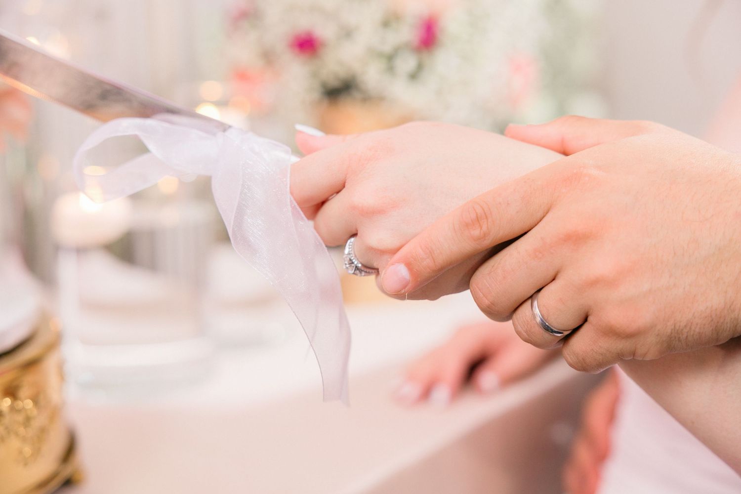 Close-up of hands with wedding rings during reception celebration.