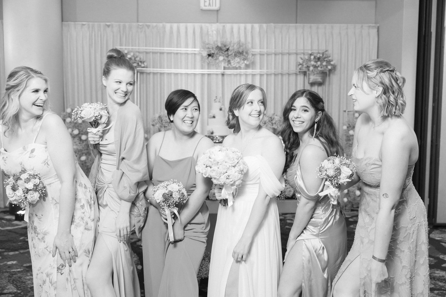 Black and white photo of bridesmaids in flowing dresses holding bouquets.