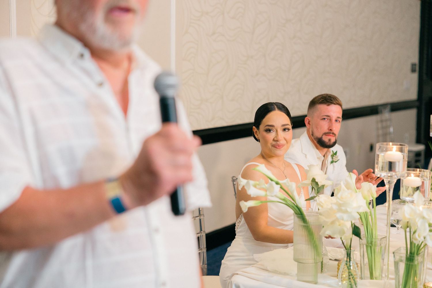 Wedding reception table features elegant white floral centerpieces and decor.