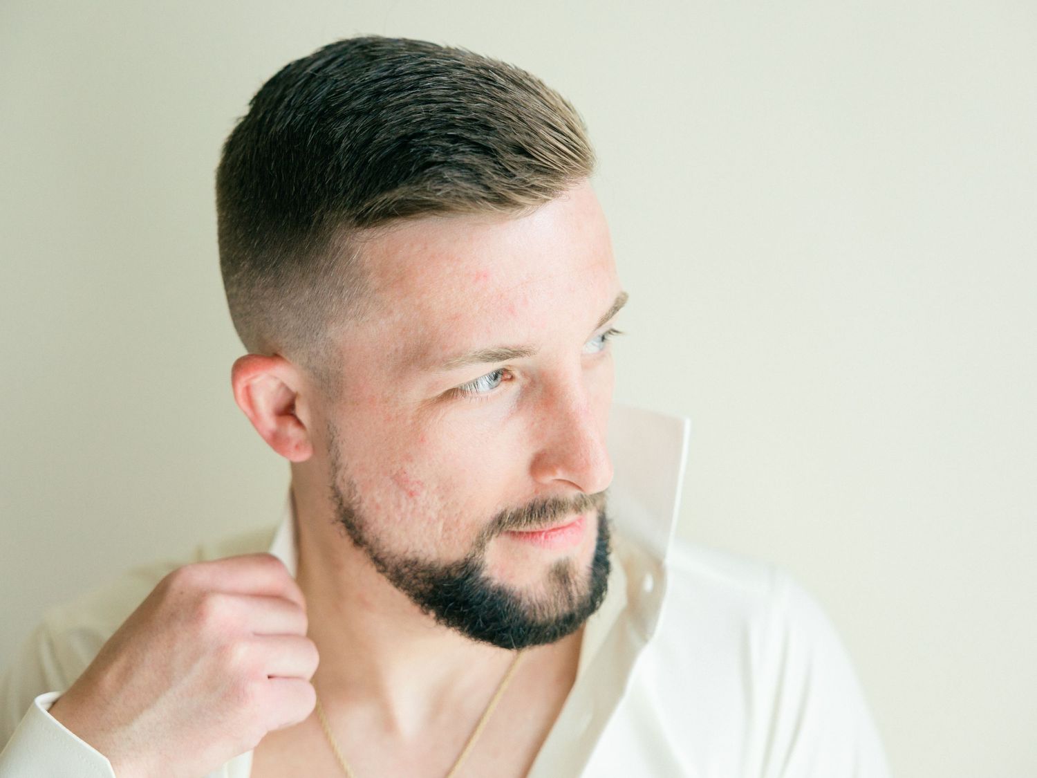 Side profile portrait in white shirt against neutral wall.