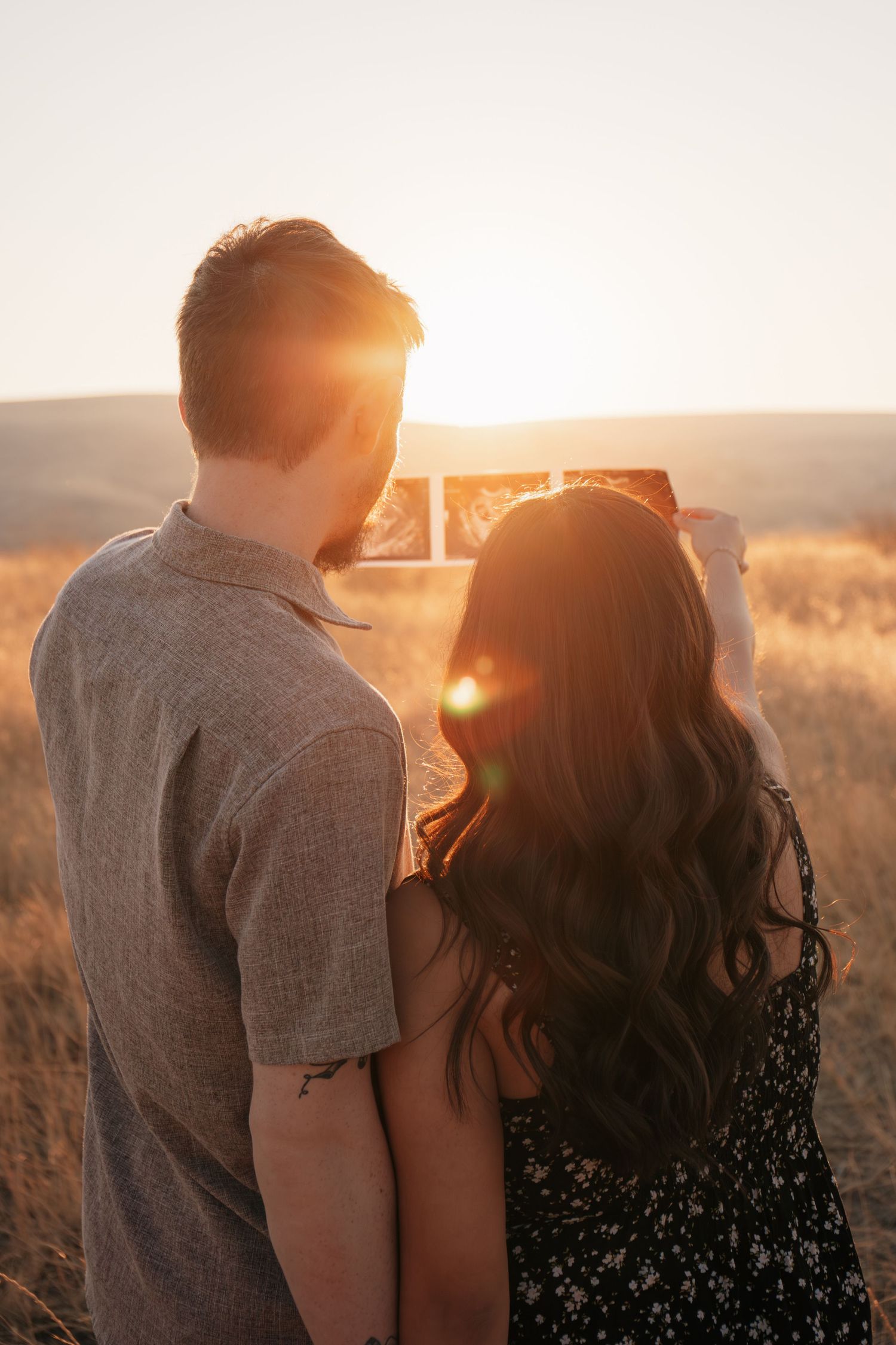 Couple holding ultrasound picture during golden hour photoshoot, Rain & Reverie photography