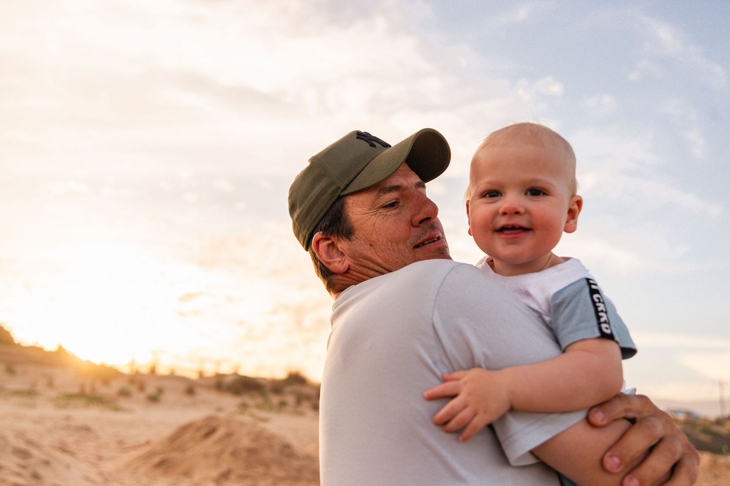Parent and baby share a happy moment outdoors during golden hour.