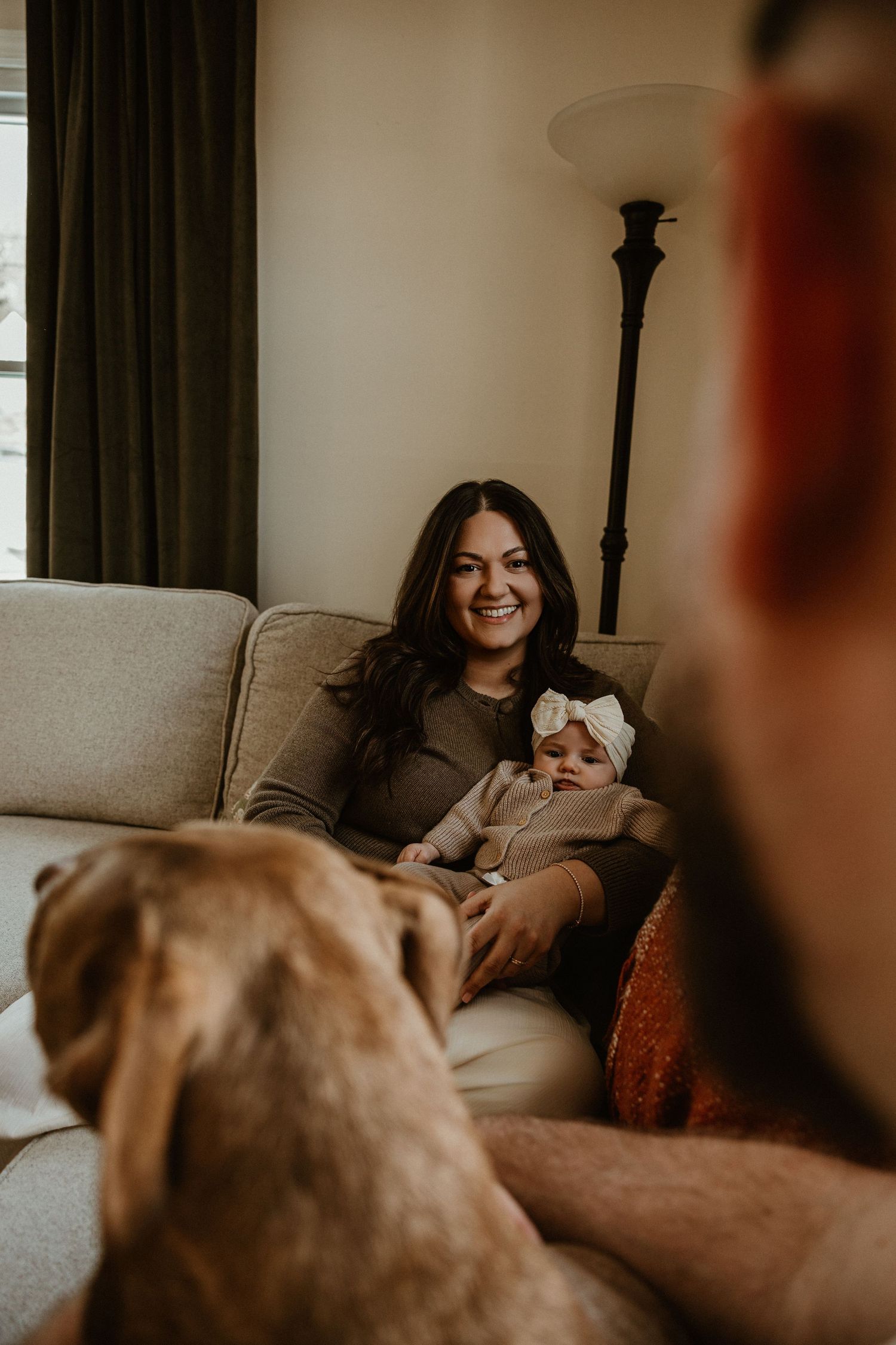 Casual family lifestyle session on a grey couch with a pet dog in frame.