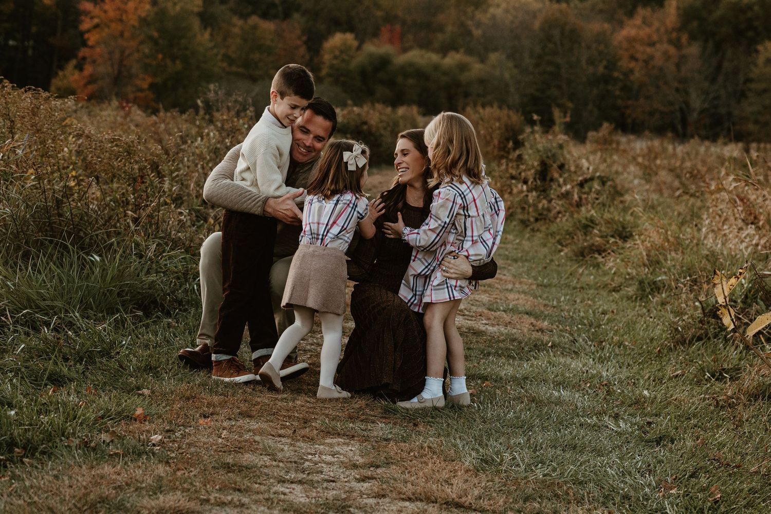 Family walking together through a scenic autumn field at dusk.