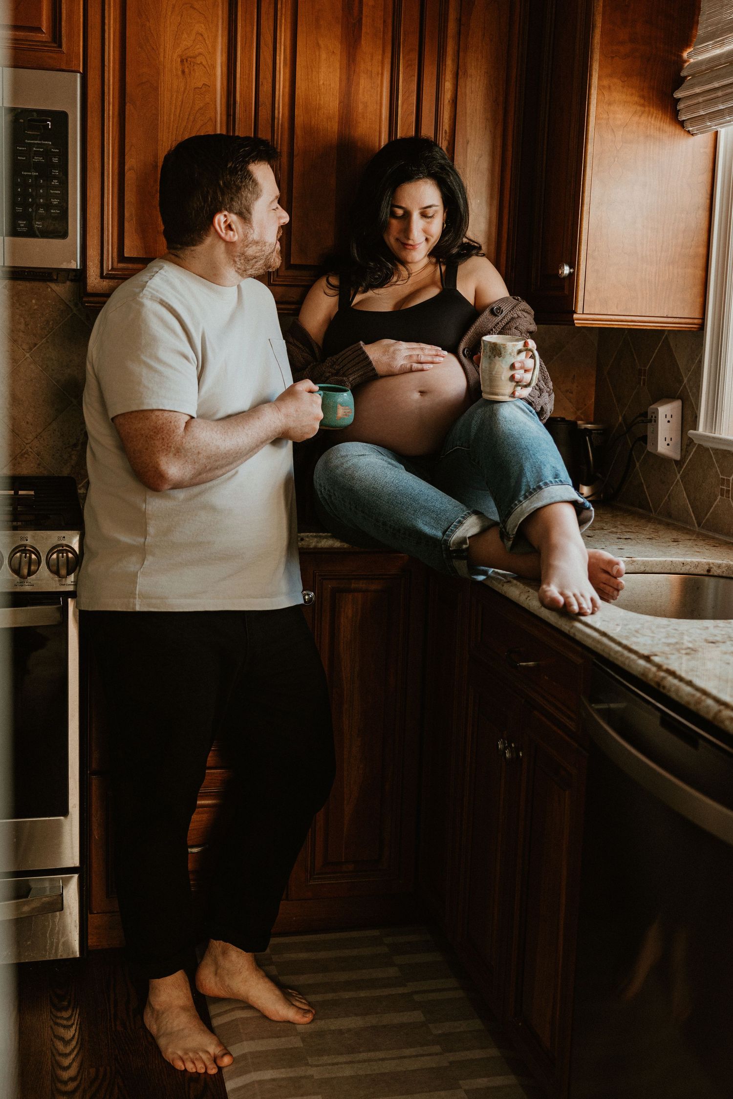 Intimate moments captured in kitchen during pregnancy photo session.