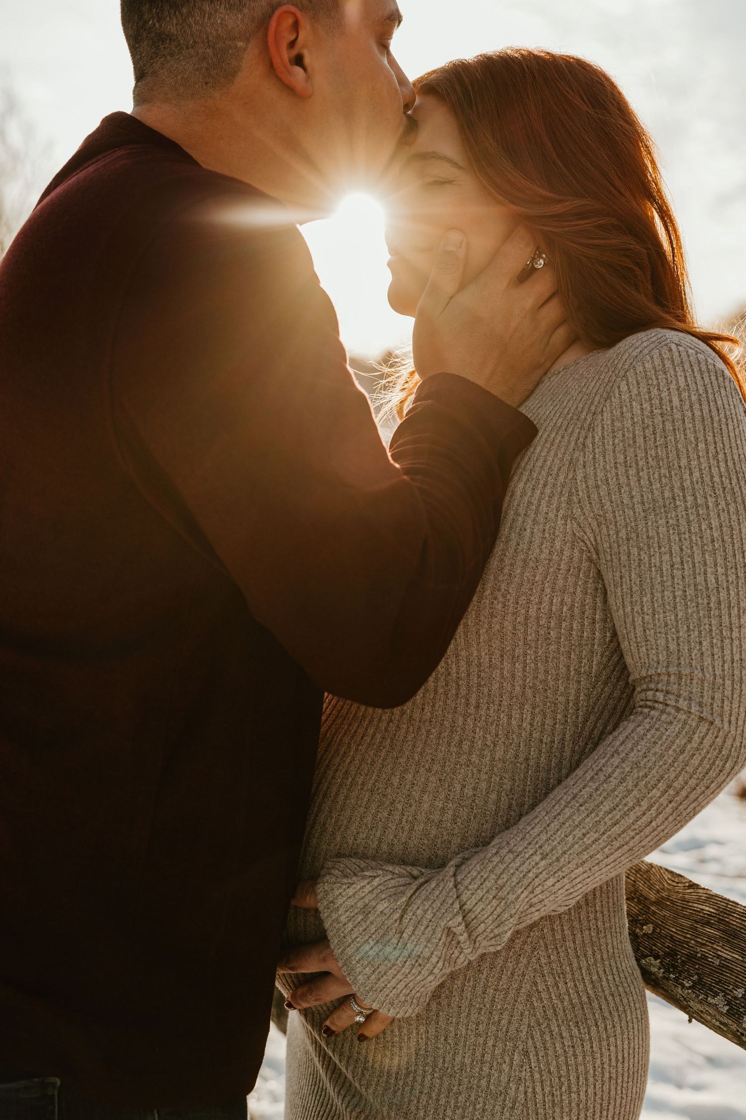 Romantic couple embraces in warm sunlight during intimate outdoor photo session.