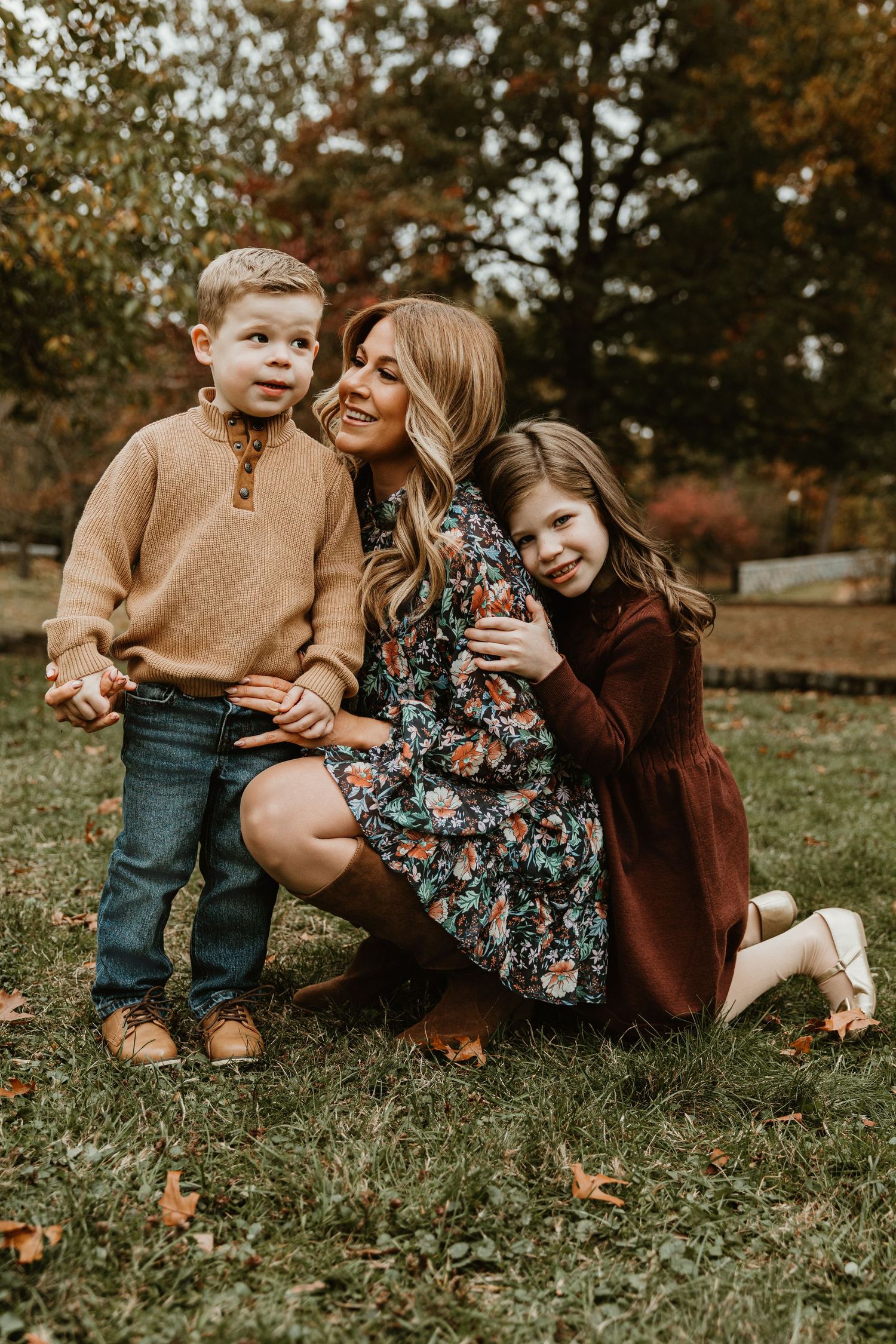 Family sitting on grass during fall photoshoot wearing coordinated brown and floral outfits.