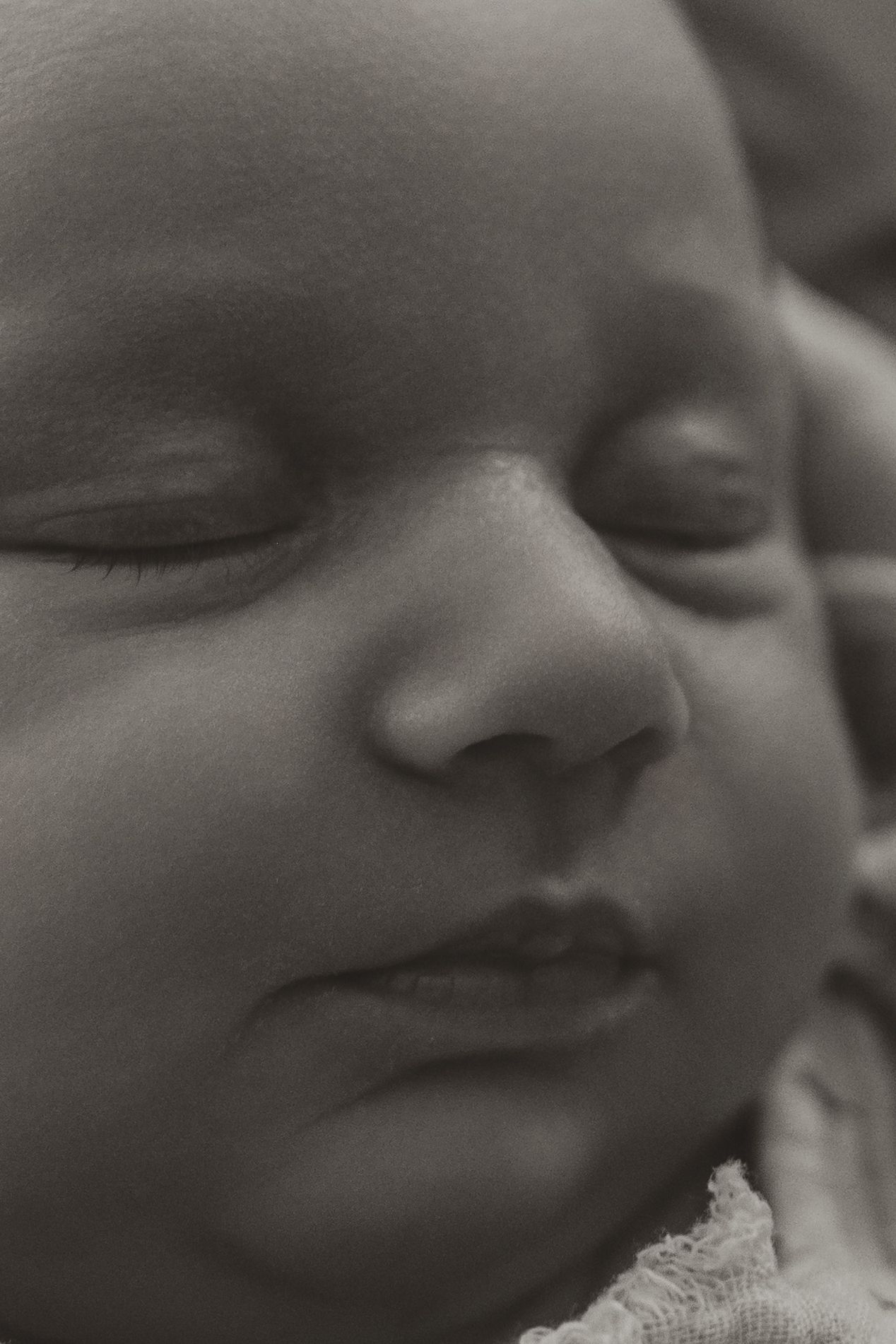 Close-up black and white portrait of a sleeping newborn baby with soft skin and peaceful expression.