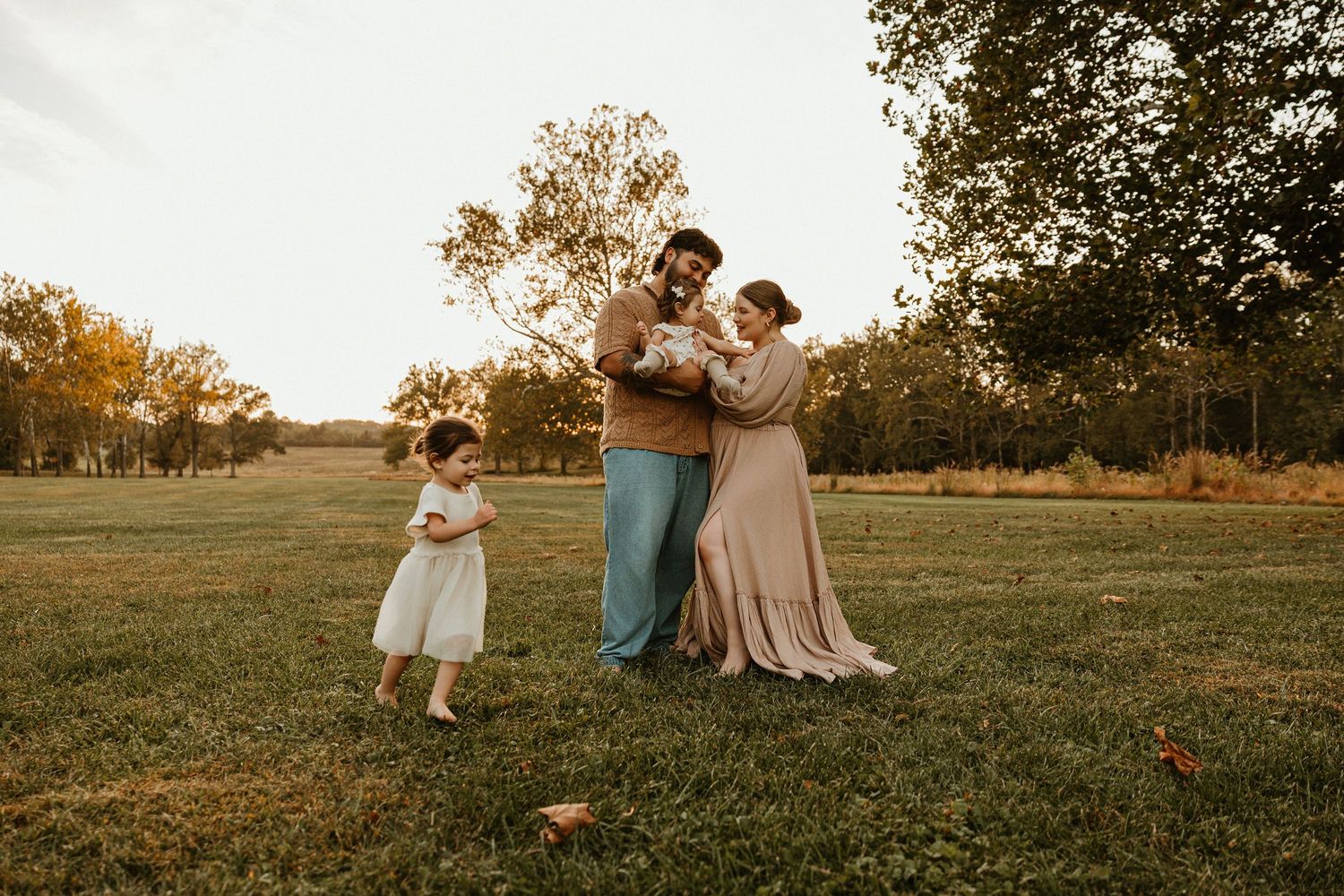 Family enjoying a warm sunset moment together in a grassy field during golden hour.