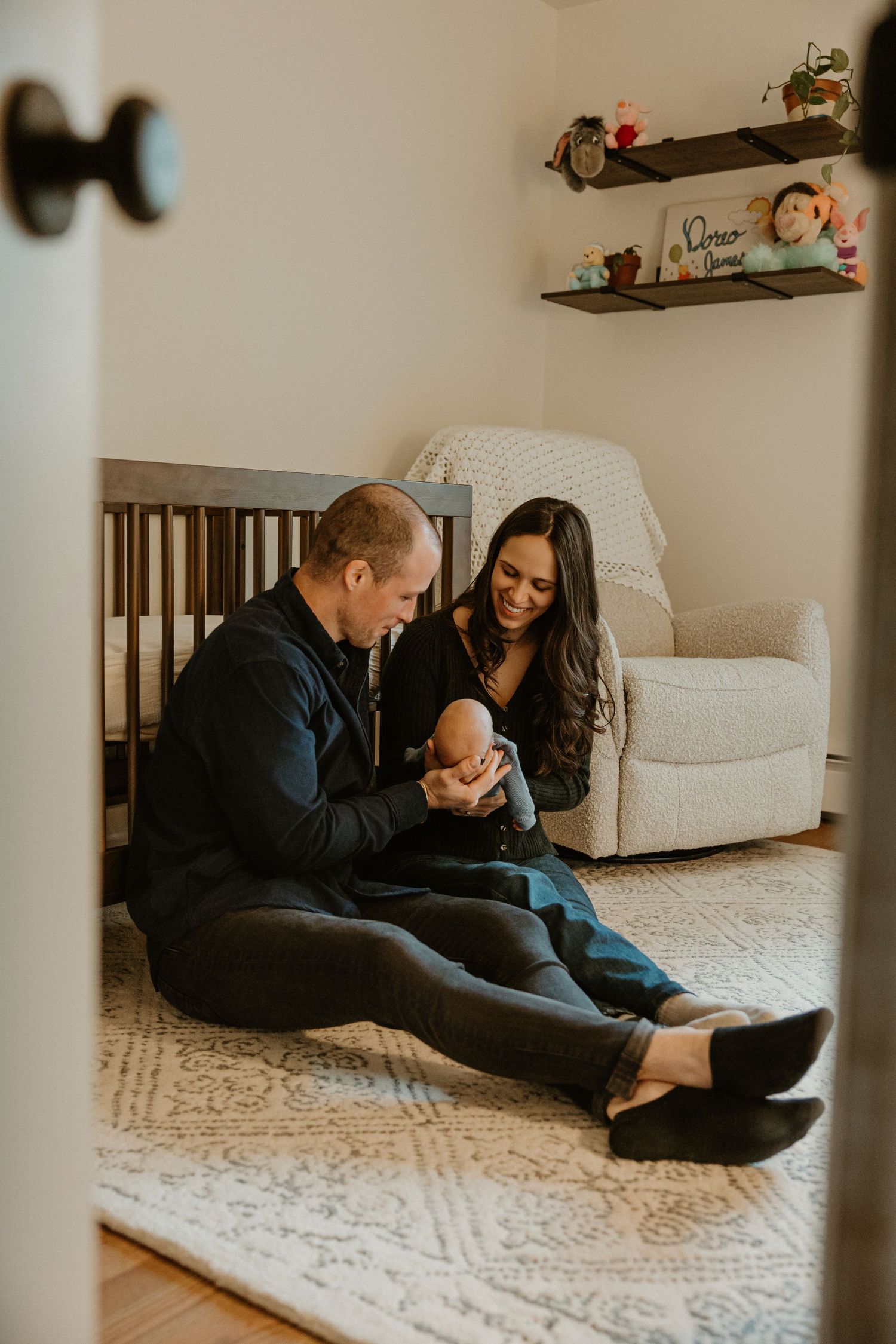 Family playing together on cream carpet in cozy nursery setting.