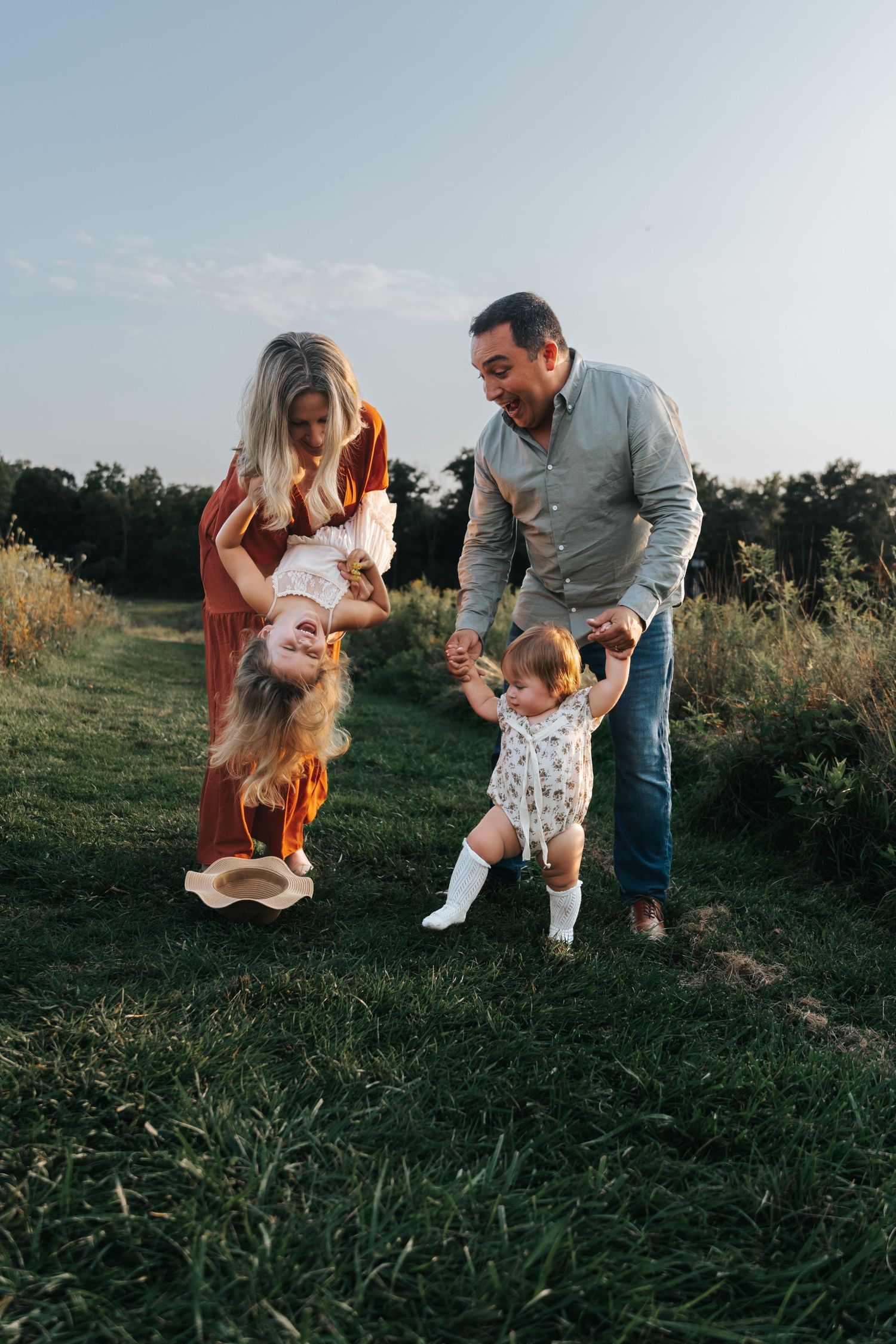Playful family moment captured in a grassy field during golden hour.