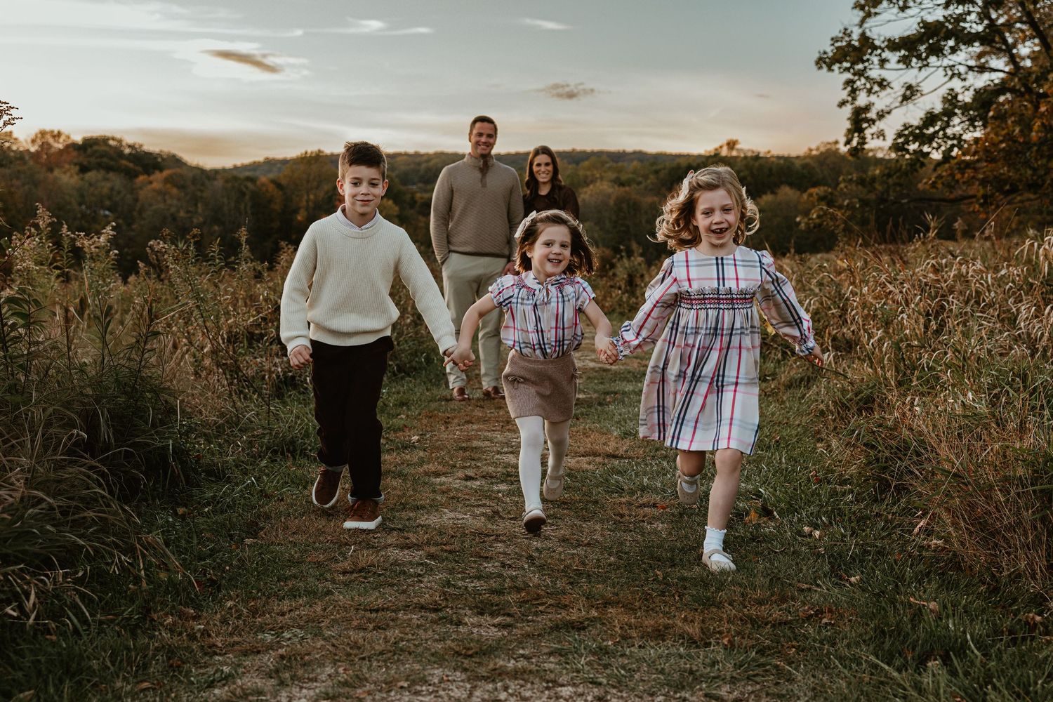 Candid family moments captured in a rustic field during sunset.