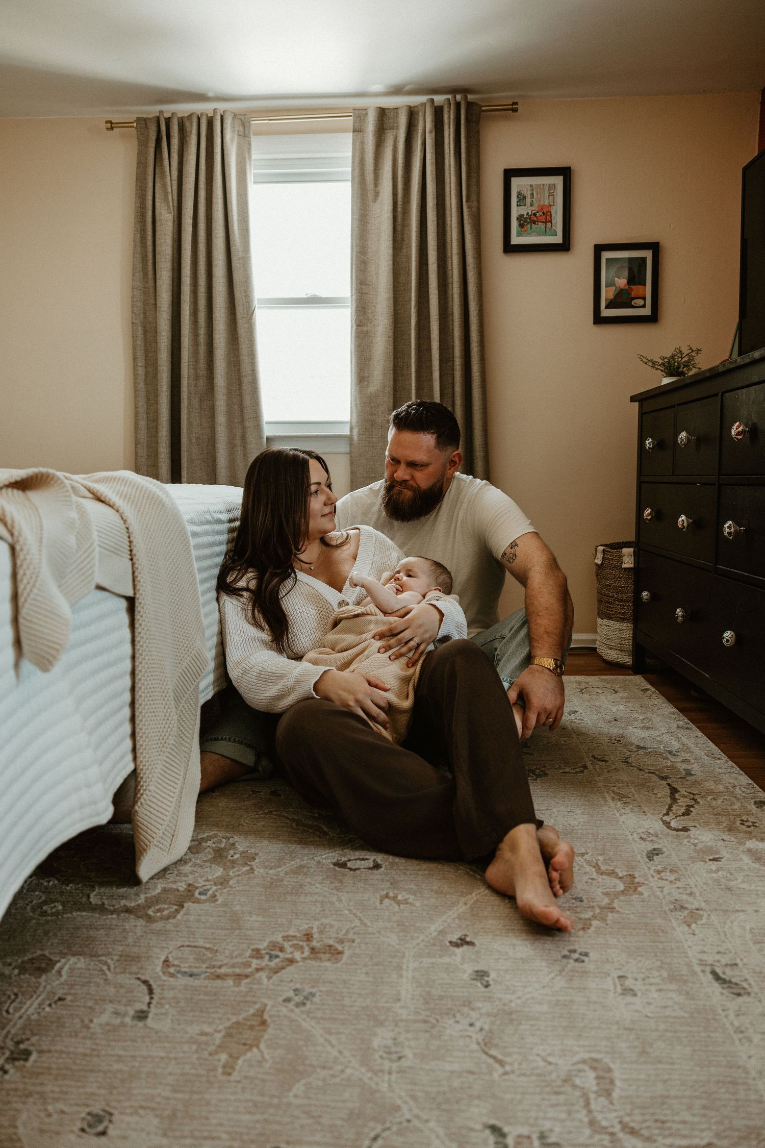 Candid family moments captured on a patterned rug during an in-home photo session.