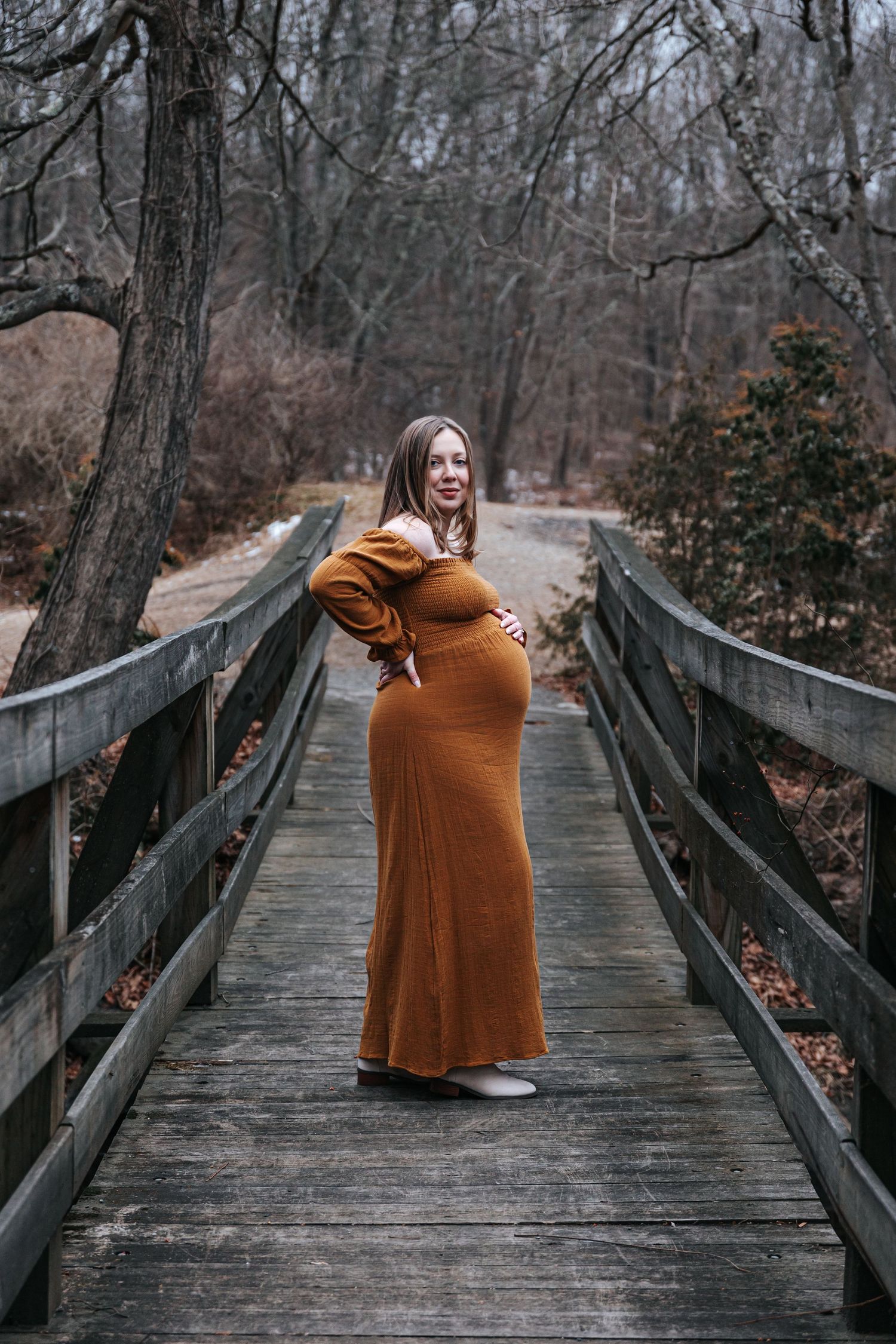 A series of photos showing a person in a brown dress standing on a wooden bridge in a winter forest setting.